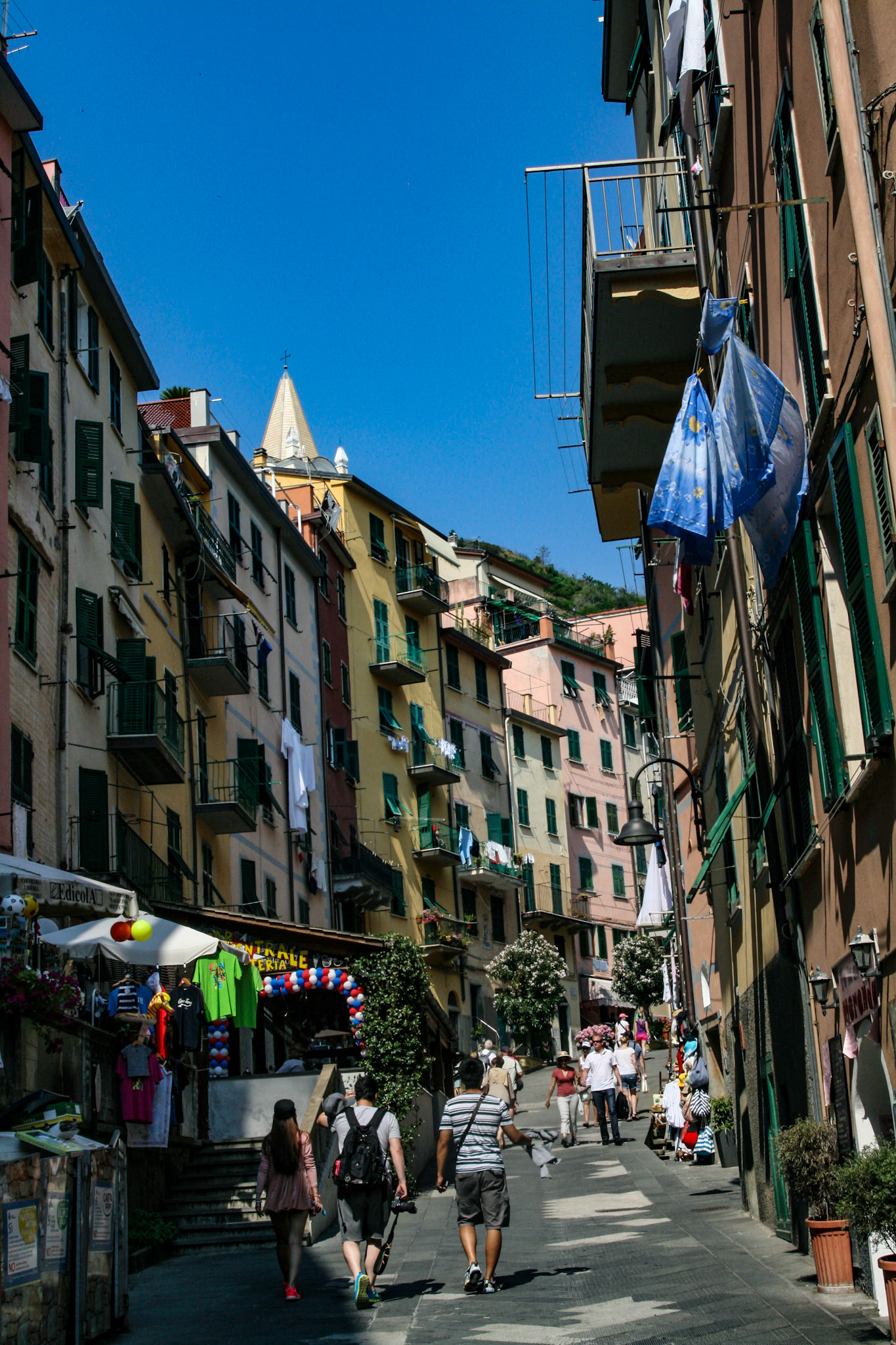 A view of Riomaggiore's main street, Via Colombo, featuring restaurants, bars, shops and happy tourists. 