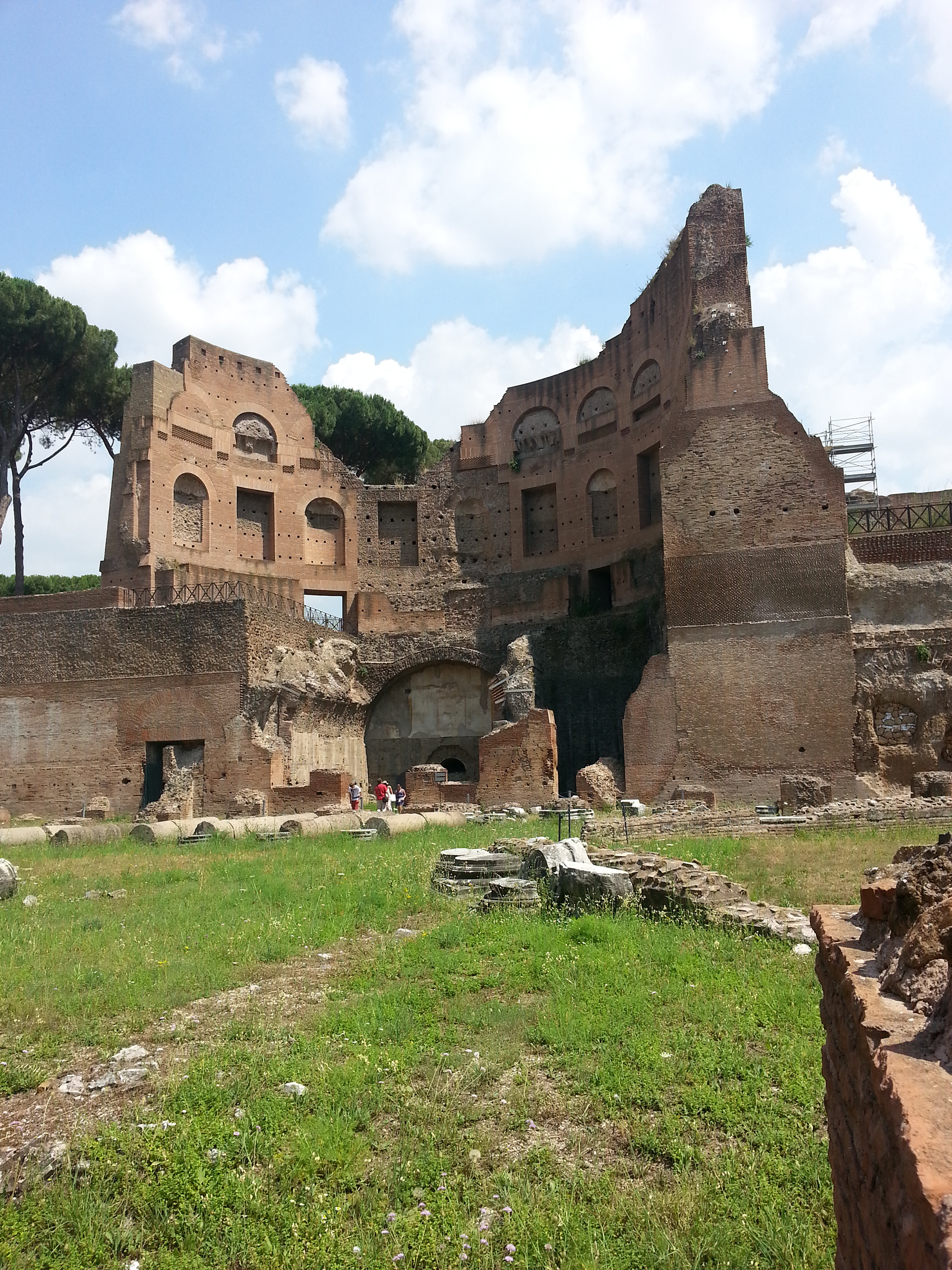 The Palatine Stadium was the third part of Domitian's palace on the Palatine Hill in Rome. It was the last to be built, after the Domus Flavia and the Domus Augustana, respectively the public and private parts of the complex. The stadium was a circus -shaped building, with a very elongated rectangle with a curved shorter side (the southern one) of about 160 x 48 meters. It occupies the entire eastern side of the Domus Augustana, for a total of about 88 meters. The perimeter was decorated by a two-story portico, composed on the lower level by brick pillars covered with marble (only the bases remain) and on the upper level by marble columns, as can be seen in part in the reconstruction of the northern corner. 