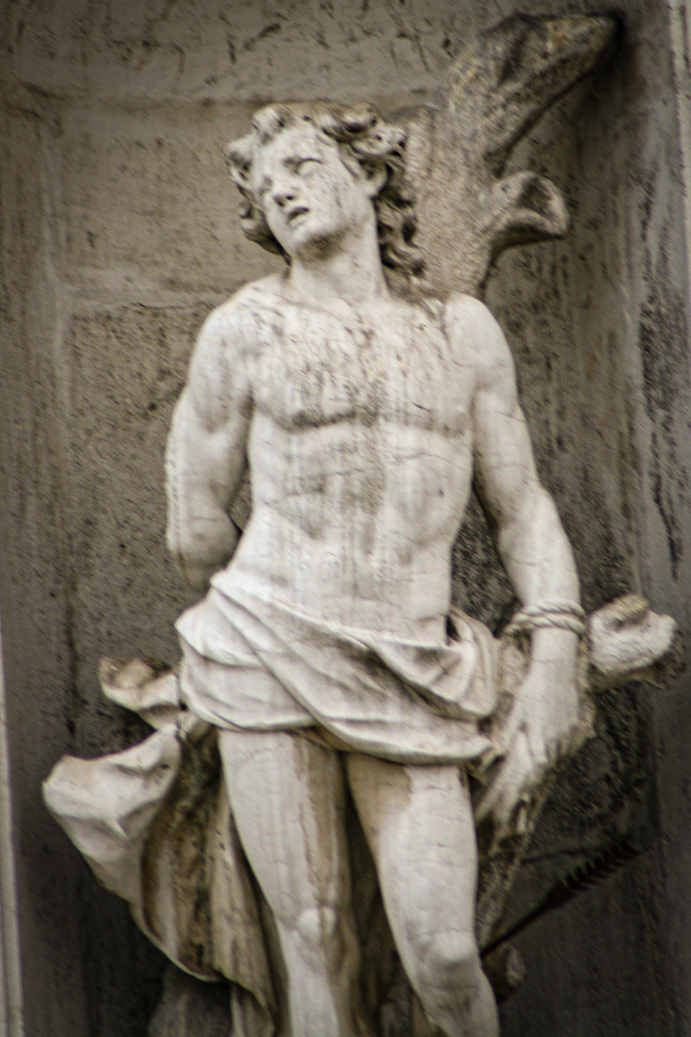 Carved stone statue of Saint Sebastian shot with an arrow. Facade of San Stae church, Venice. 