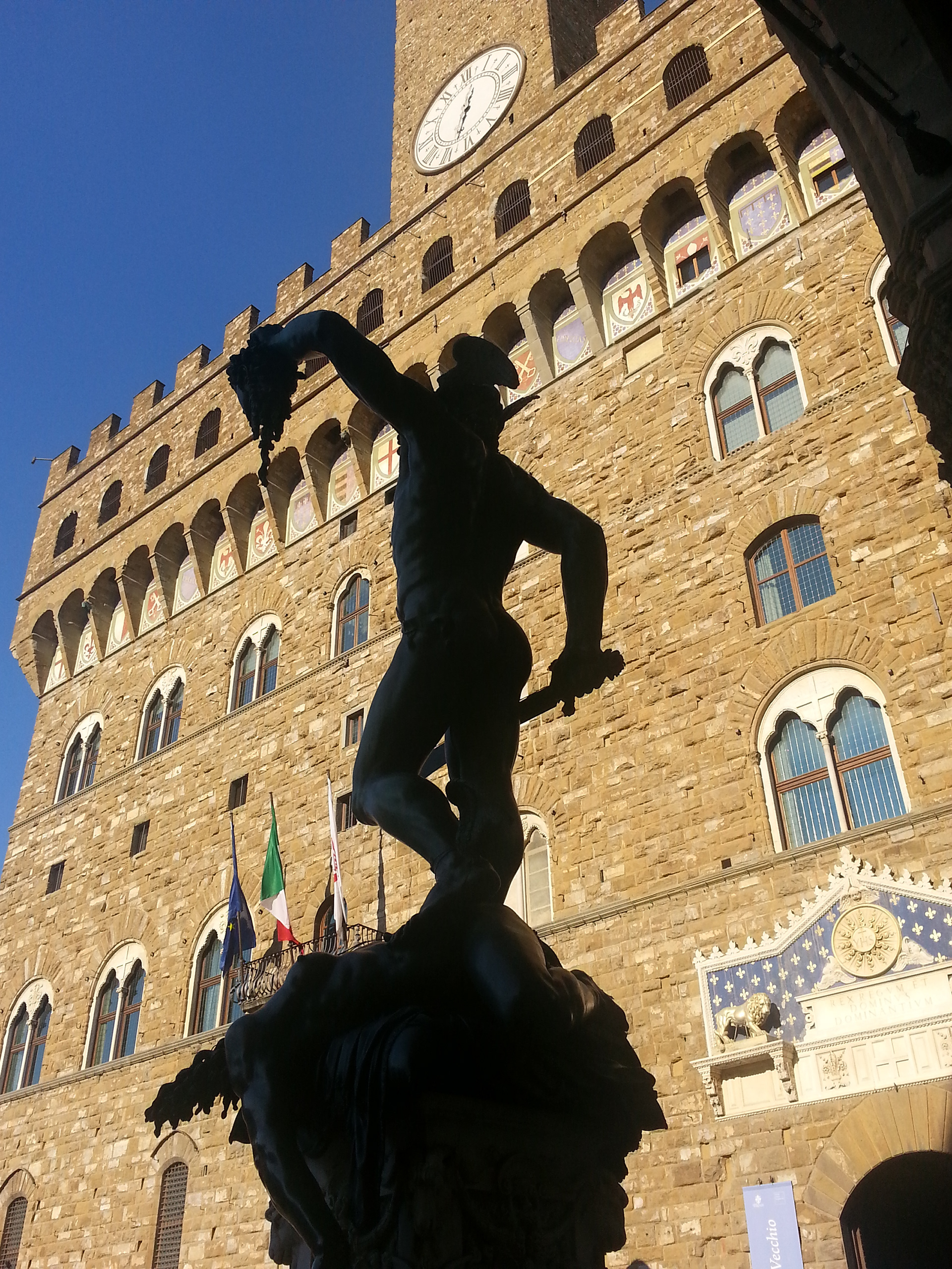 Perseus Medusa Statue, Loggia dei Lanza, Piazza della Signoria, silhouetted against the Palazzo Vecchio Florence Italy. Perseus statue created 1500s by Benvenuto Cellini. 