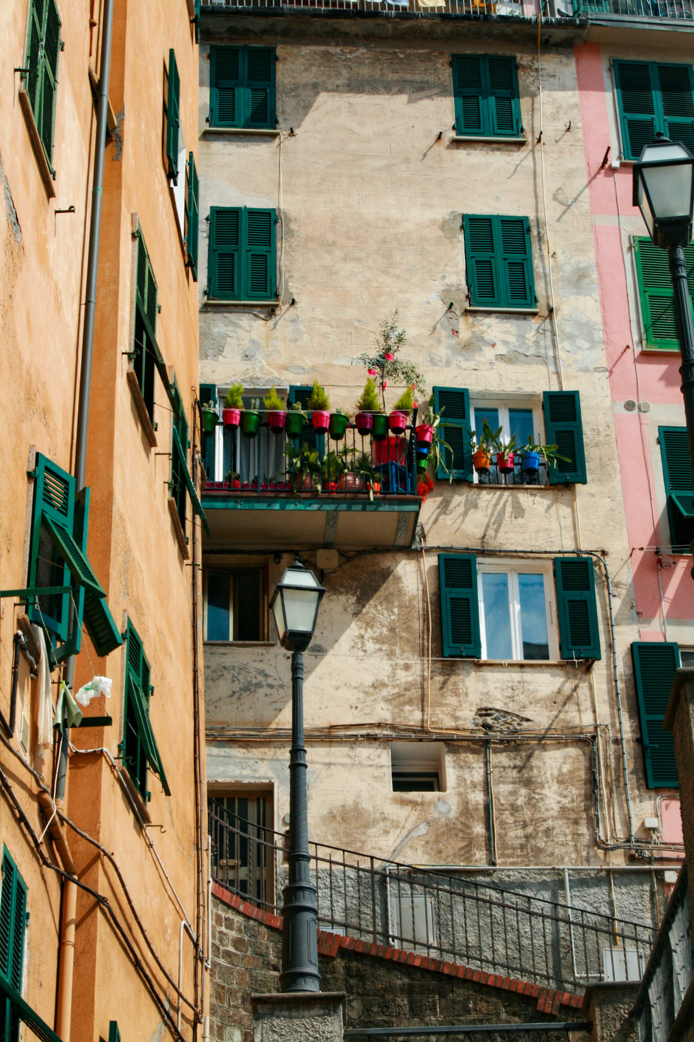 Balcony with flowers and windows with green shutters