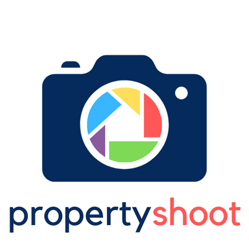 A navy blue camera with rainbow-colored lens capturing the image of a house within its negative space. The logo embodies creativity and inclusivity, suggesting a vibrant and welcoming approach to photography and home representation for Property Shoot