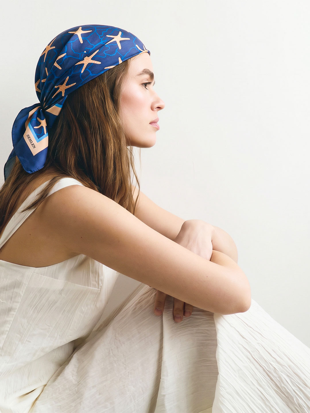 Beyaz elbiseyle lacivert deniz yıldızı desenli Sehlen bandana kullanan kadın model