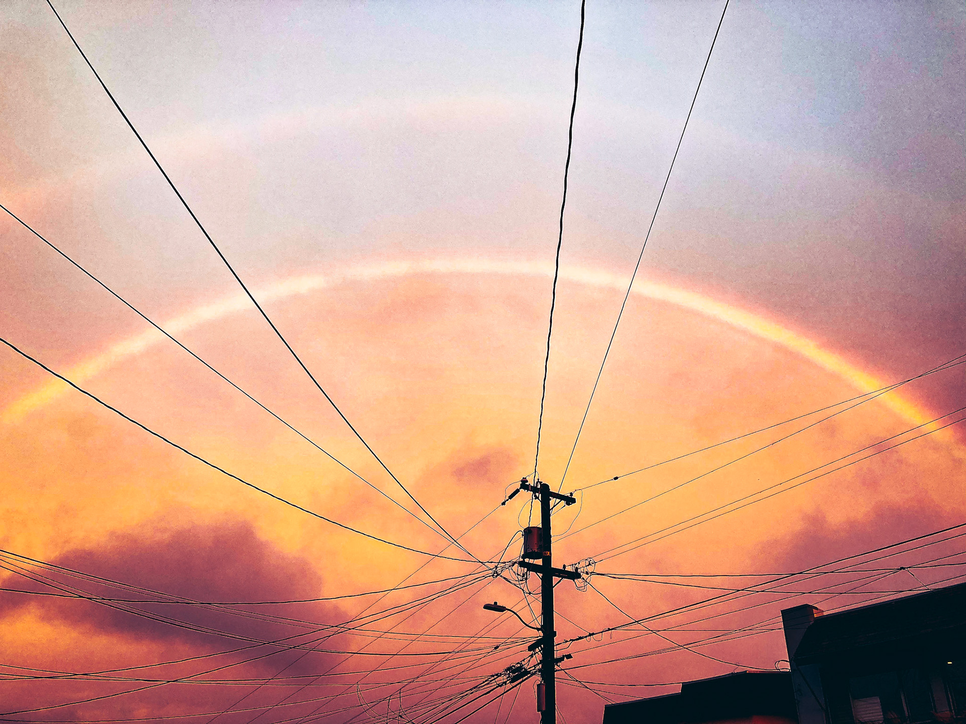 power lines meet at a point surrounded by a double rainbow