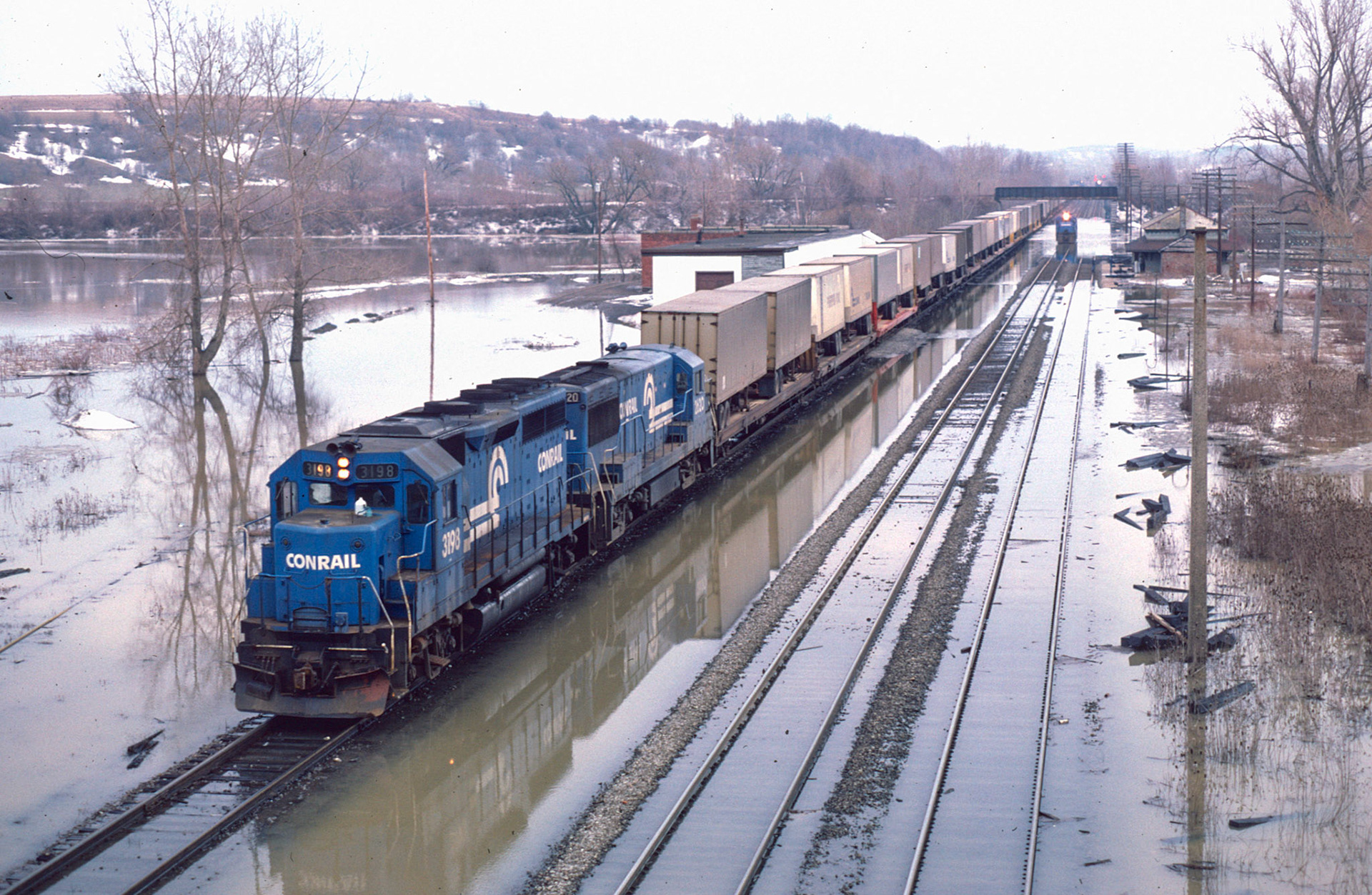 A westbound TV train crawls down the controlled siding as a single unit tests the trackage under the Sodus branch bridge as another westbound waits its turn through the mess.