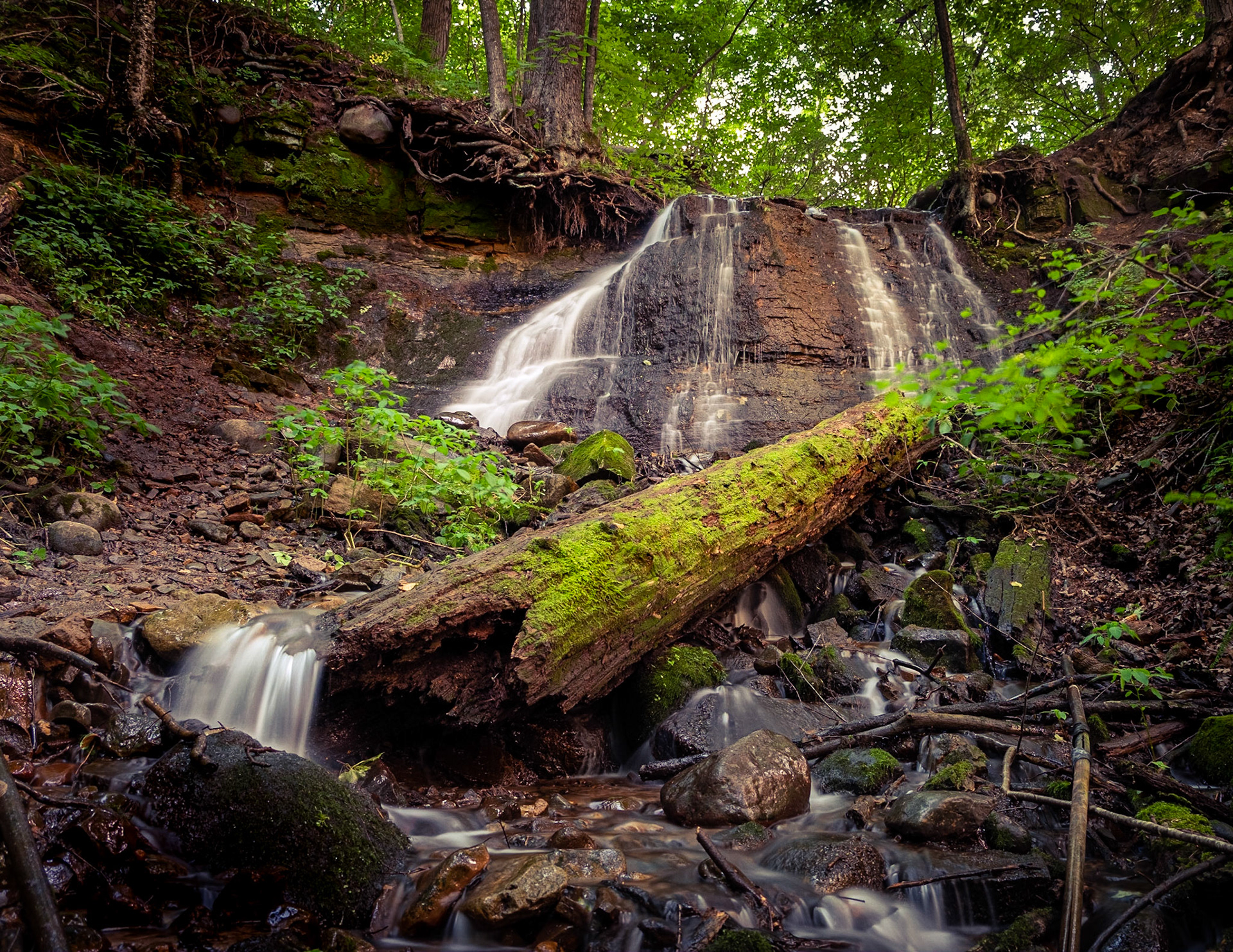 Falls Do Me In Every time -  Leaving work for the day I wanted to see if I could head to these falls before night fall. After an hour drive and a 3 mile hike in some rather rough rocky and hilly terrain along with an insane amount of mosquito's following me every step of the way, I reached the end of the trail. They weren't the grandest of falls, but they were a nice spot to take a break and enjoy the cool mist and a very lush valley of furn before heading back... in the dark. Sometimes, it is the journey that makes the end the reward.