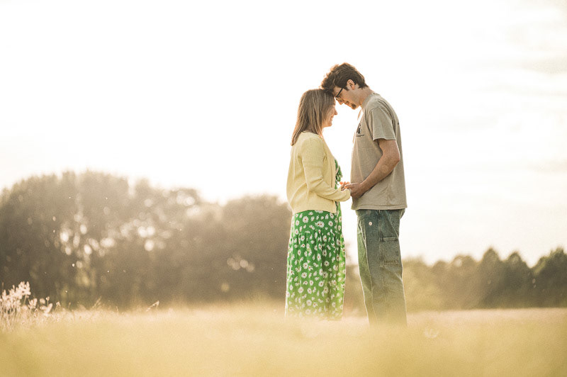 Annie and Joe walking hand in hand during a relaxed pre-wedding photoshoot on Lincoln West Common in warm evening sunlight, capturing natural candid moments and soft golden light.
