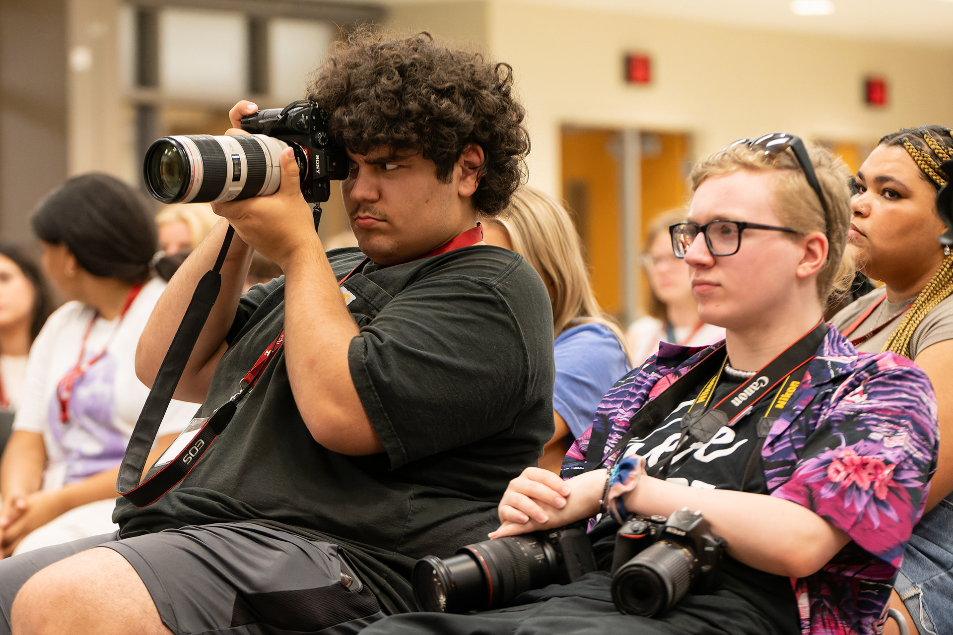 JT Frenzel, left, shoots photos of counselors as Kadin Bright looks on during a meeting on the first day of the Indiana University High School Journalism Institute, Monday, July 8, 2024, in Bloomington, Ind. Frenzel and Bright, Indiana residents, enrolled into the photojournalism workshop at HSJI. (Vincent Hsiao/HSJI)