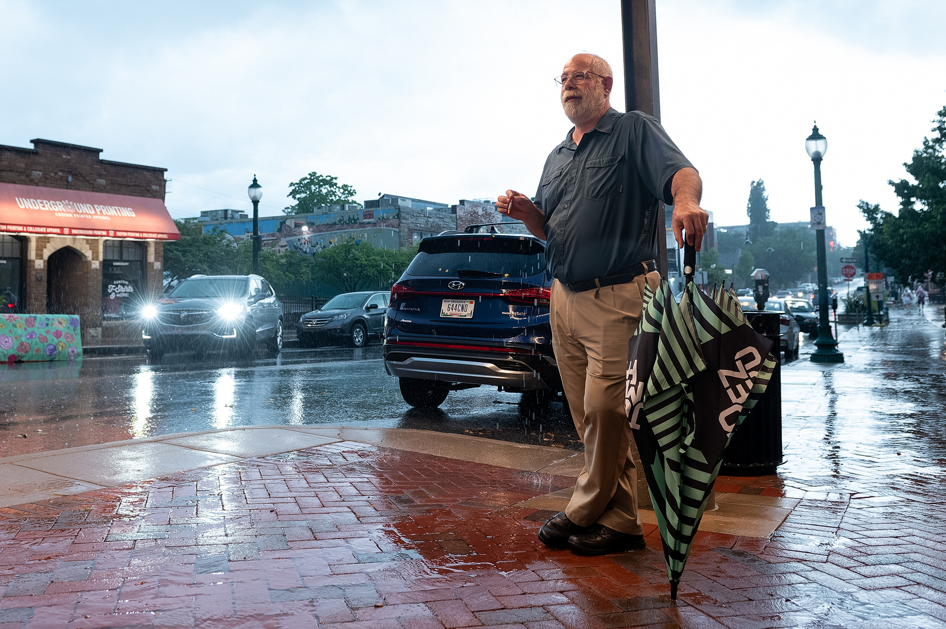 A man stands under a canopy in front of a Noodles and Company restaurant during a thunderstorm, Tuesday, July 9, 2024, on Kirkwood Avenue in Bloomington, Ind. The weather was a result of remnants of Hurricane Beryl, which struck parts of southern North America earlier in the week.  (Vincent Hsiao/HSJI)