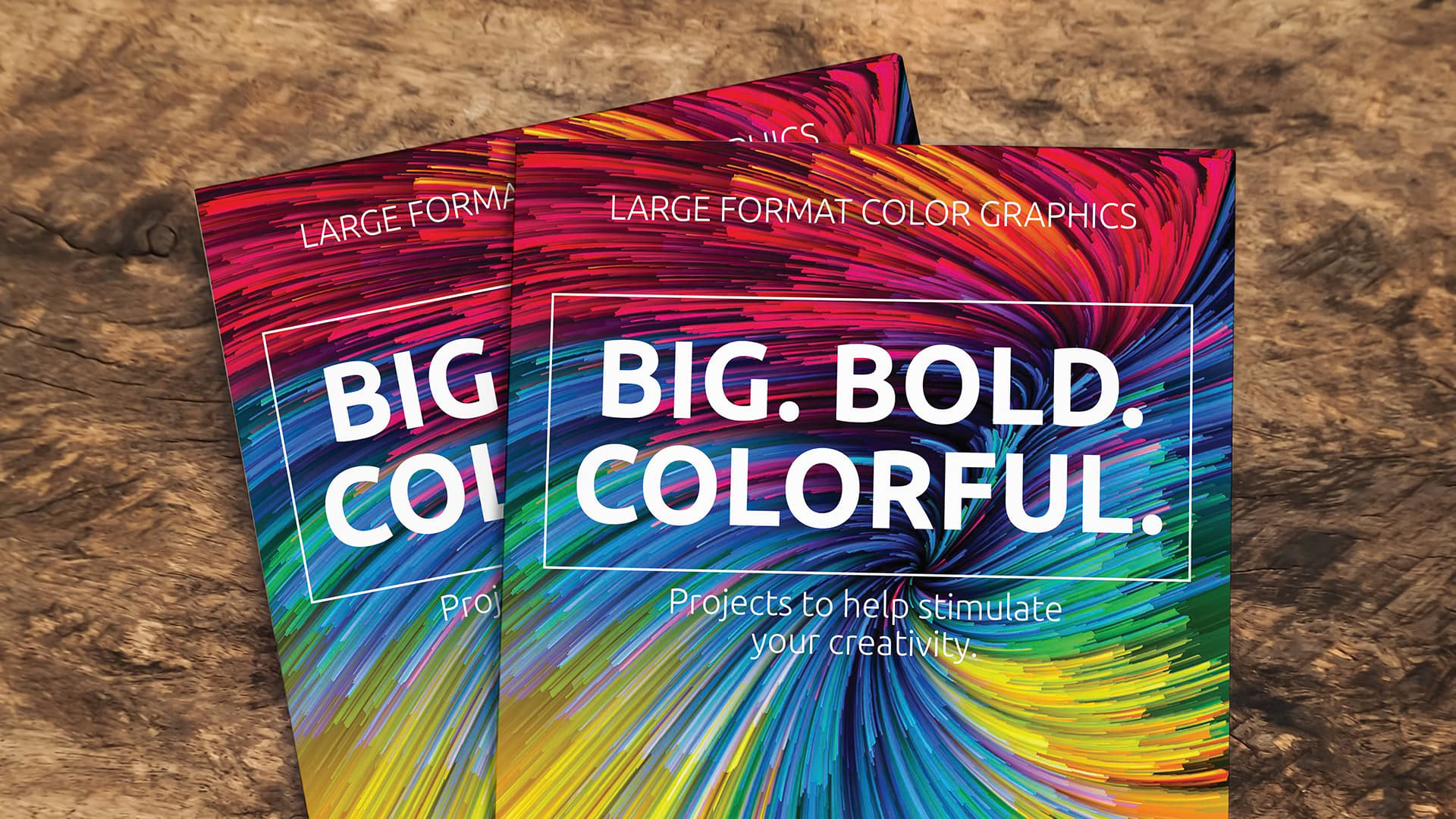 large format color brochures fanned out on a wood desk