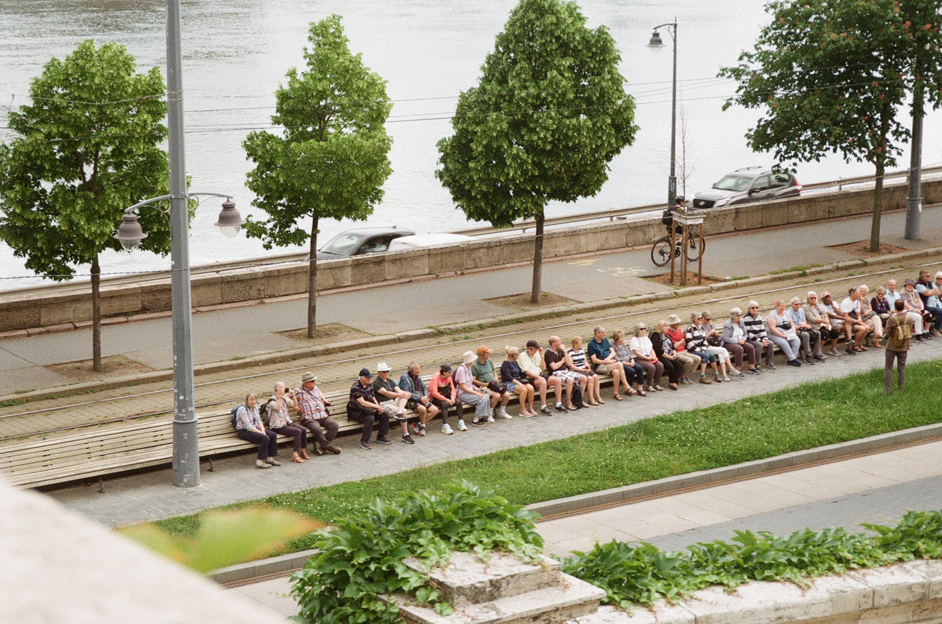A group of middle and old aged tourists listen to their guide in Budapest, Hungary. May 2024.
