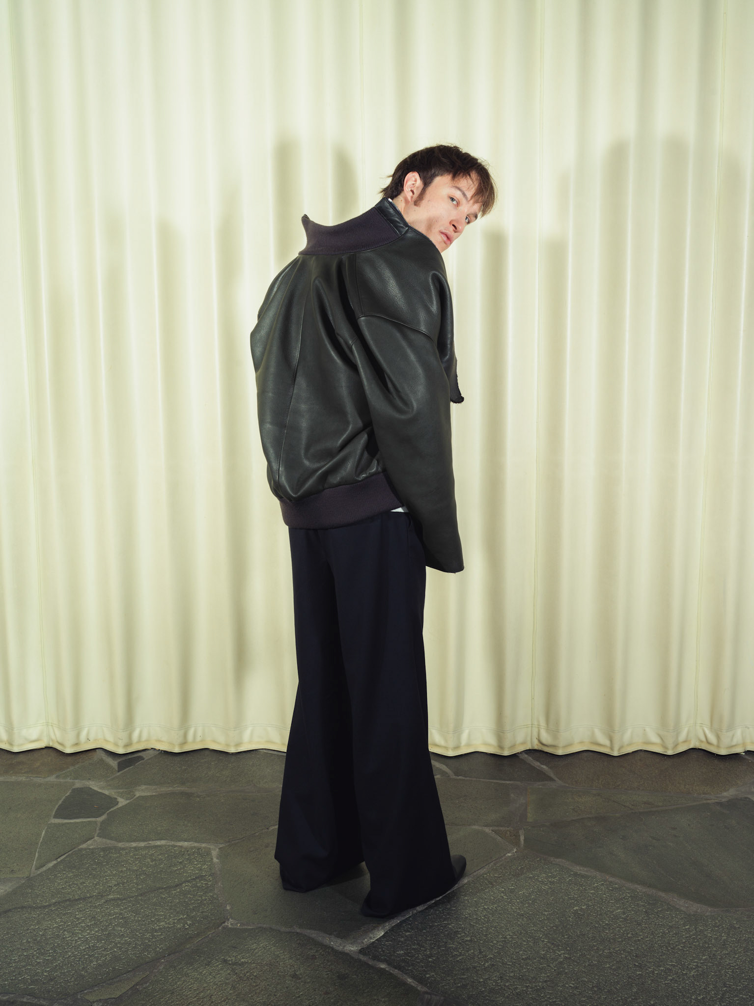 Raw edge calfskin leather jacket with handmade silver zipper tabs, Cotton poplin henley shirt with handmade ceramic buttons, Pleated wide-leg pinstripe wool trousers