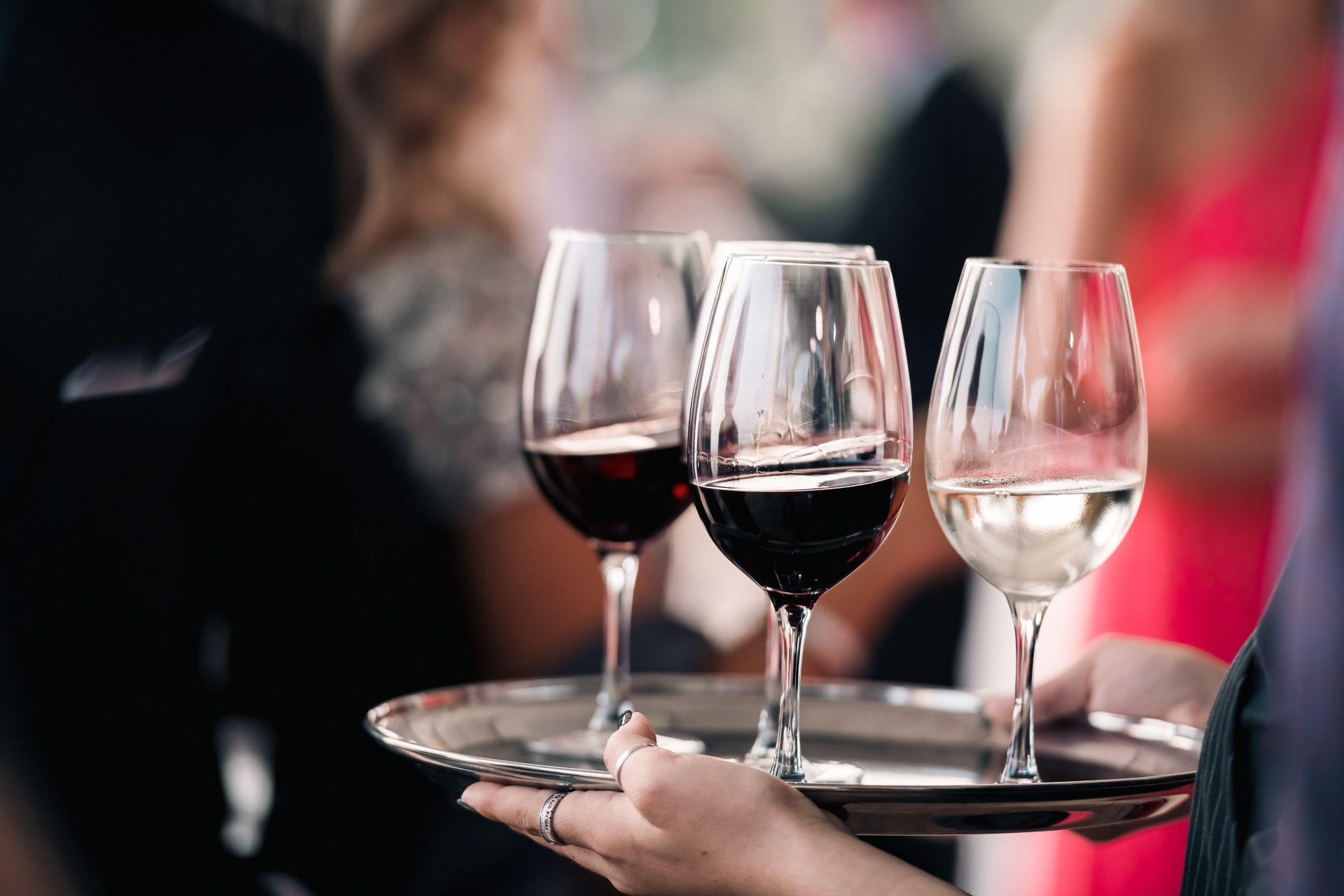 Close-up of three wine glasses being carried during reception cocktail service.