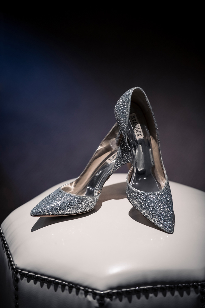 Sparkling silver bridal heels styled on upholstered stool.