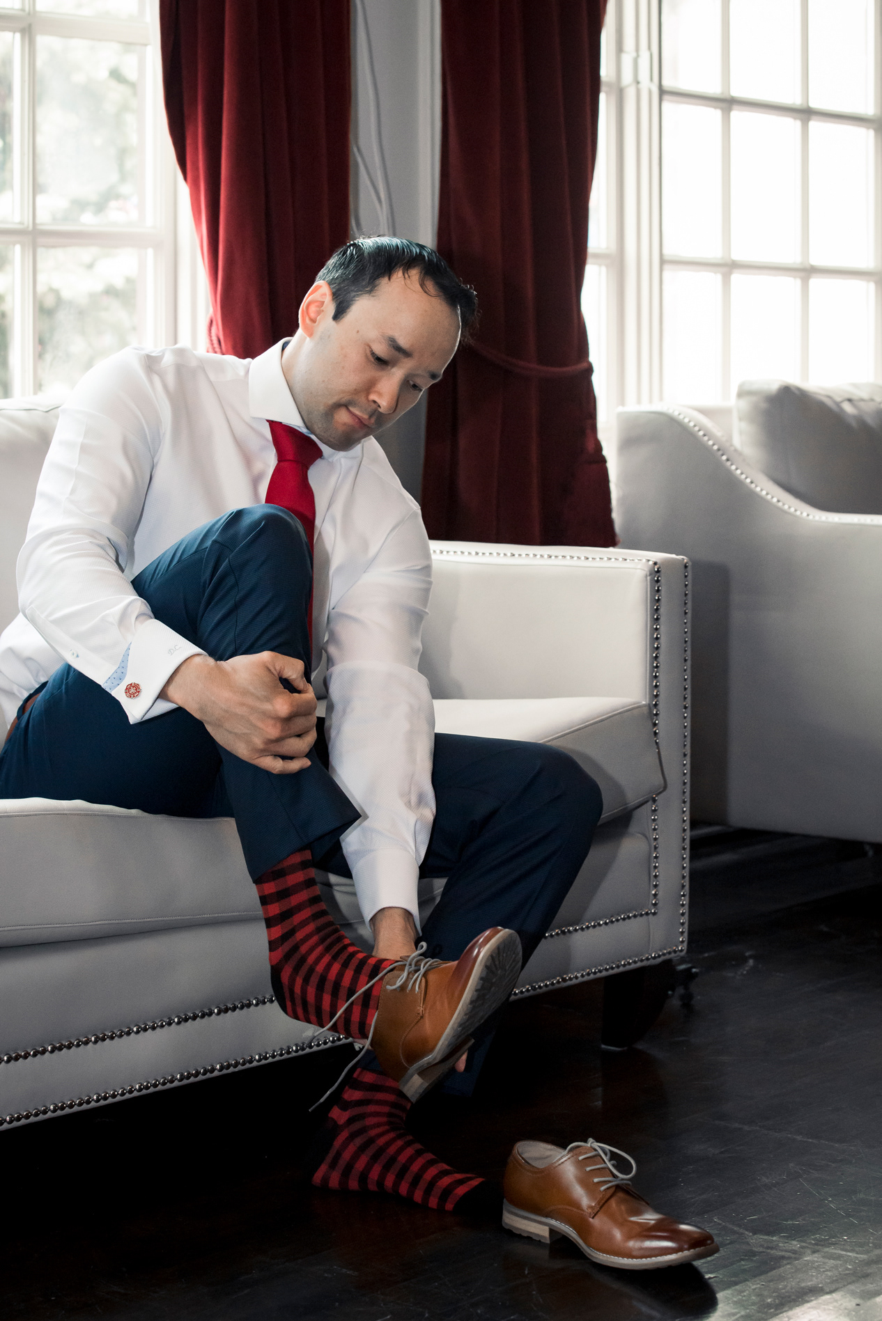 Groom putting on shoes, wearing checkered socks.