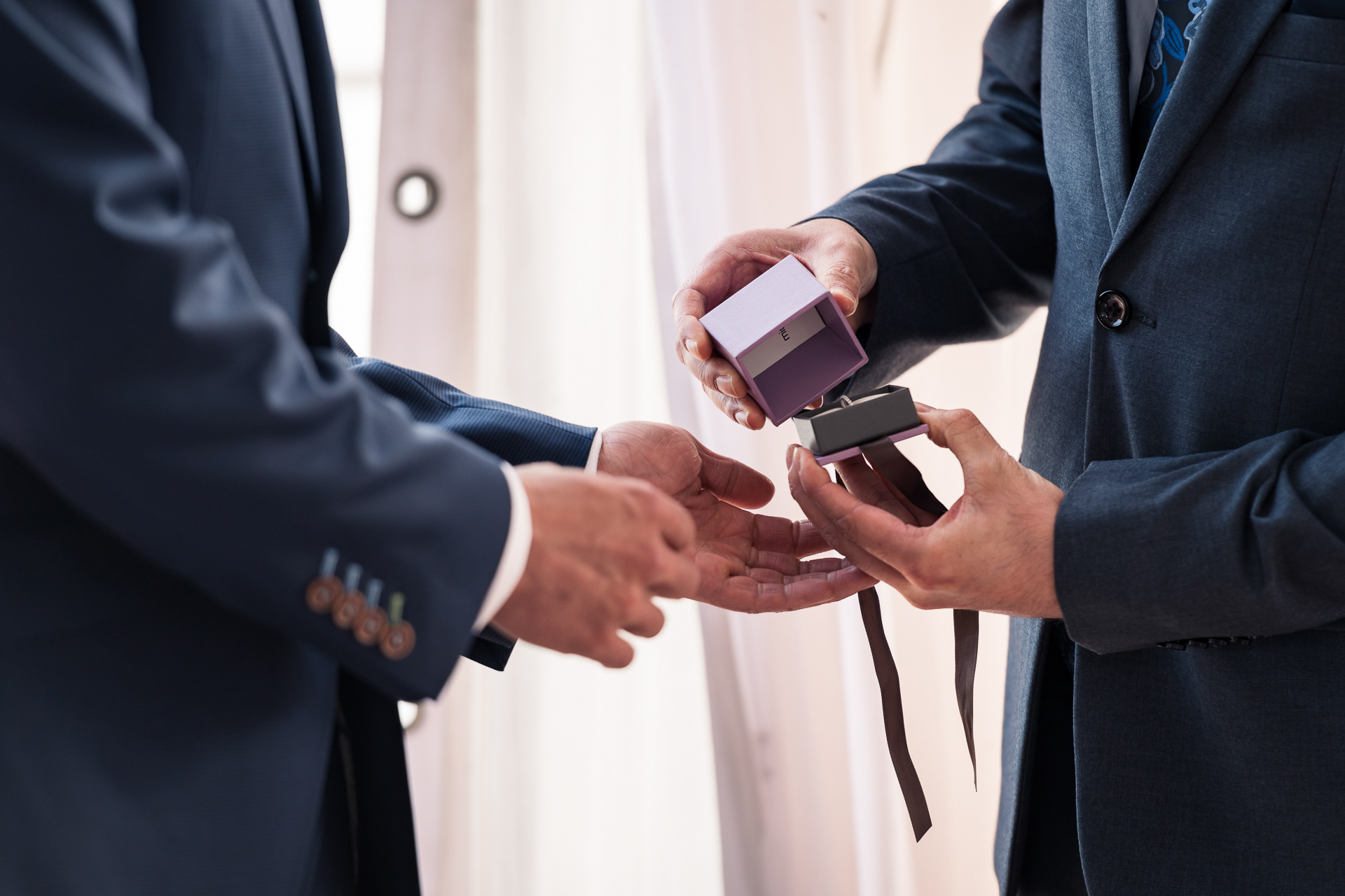 Close-up of groom opening the ring box during wedding ceremony.