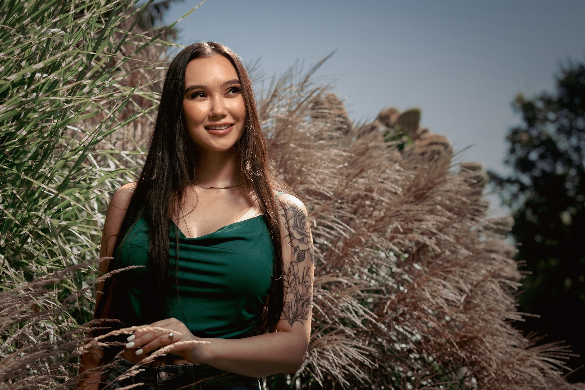 Portrait of bride-to-be smiling while standing among tall ornamental grasses at Guild Park.