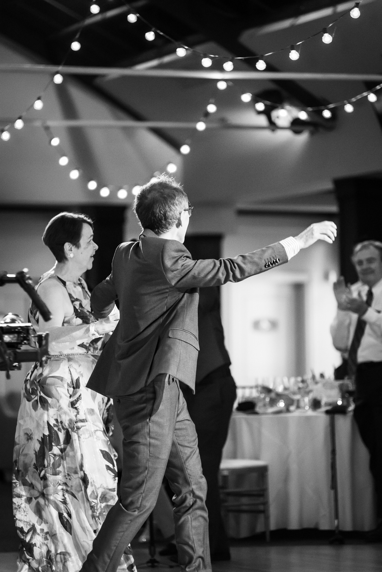 Black and white candid of guests dancing during reception entrance.
