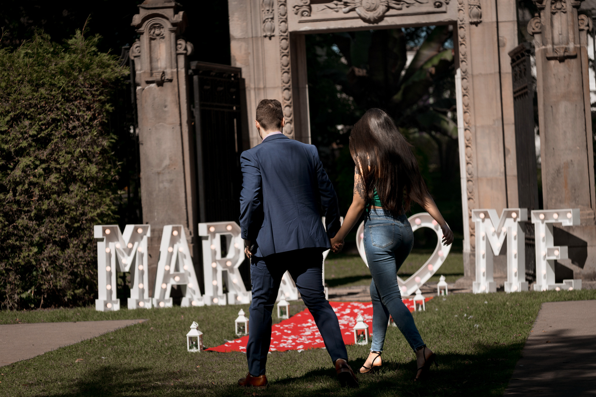 Couple walking together hand-in-hand toward the proposal setup at Guild Park.