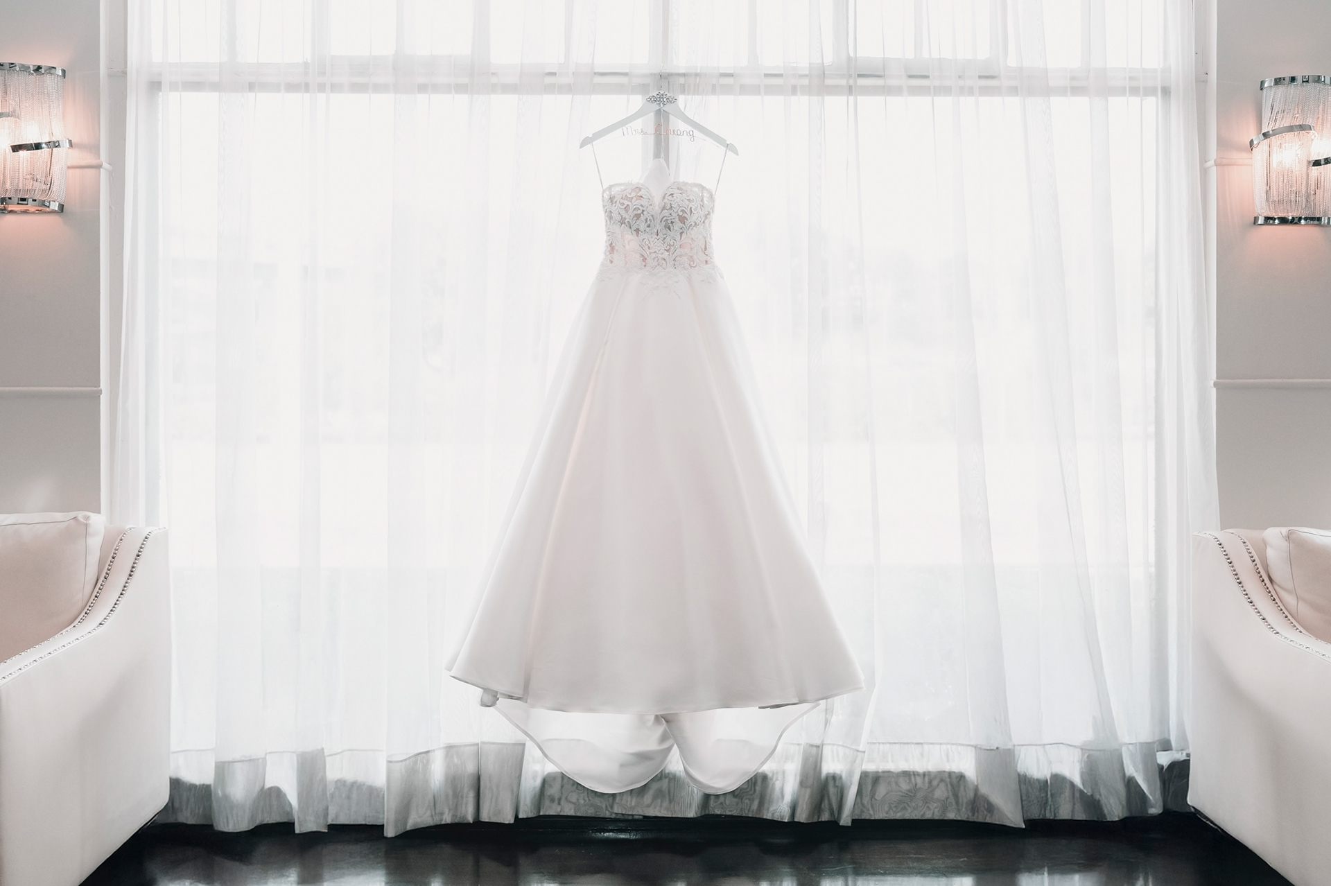 Wedding dress hanging by a window with sheer curtains at Palais Royale.
