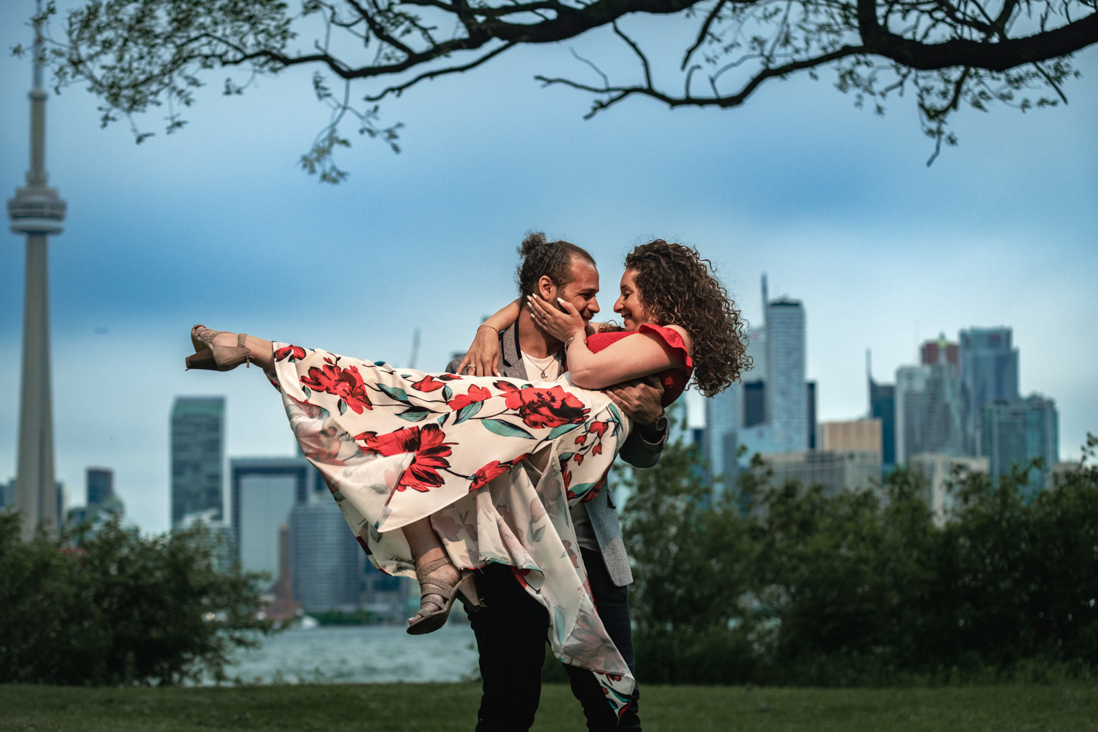 Playful moment with groom-to-be lifting his fiancée against the Toronto city skyline backdrop.