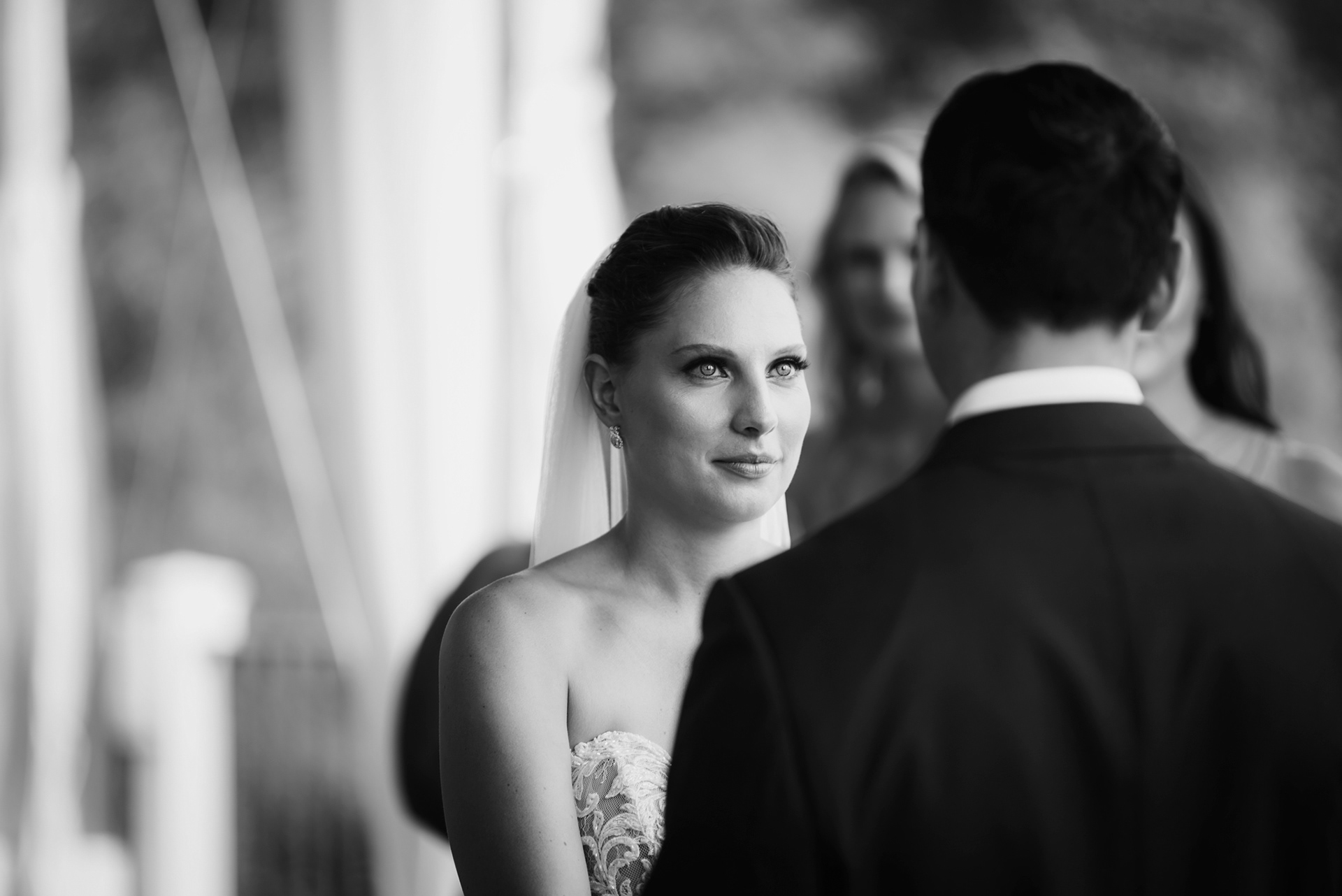 Black and white close-up of bride looking at her groom during the ceremony.