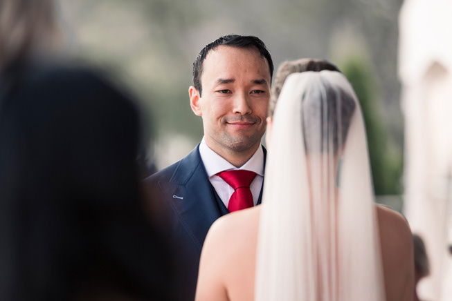 Groom smiling warmly at his bride during their outdoor vows.