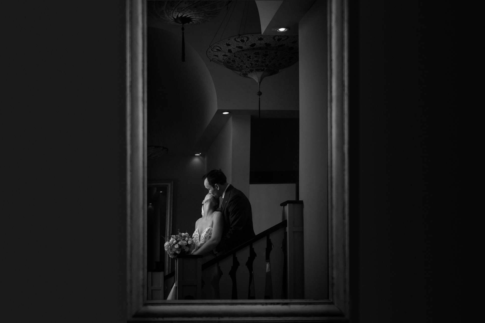 Black and white romantic portrait of couple sharing a kiss on a staircase.