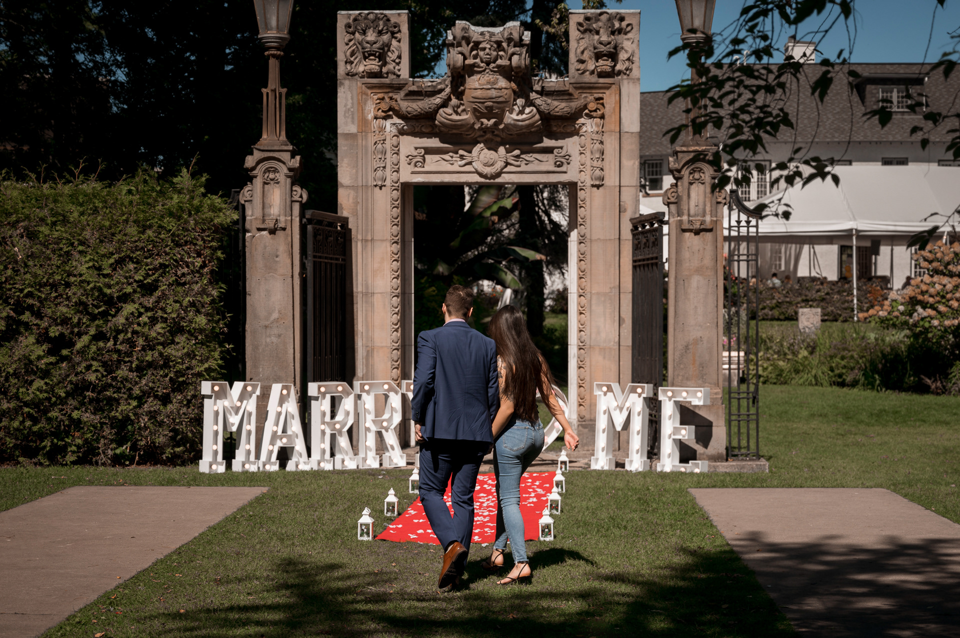 Couple walking together hand-in-hand toward the proposal setup at Guild Park.