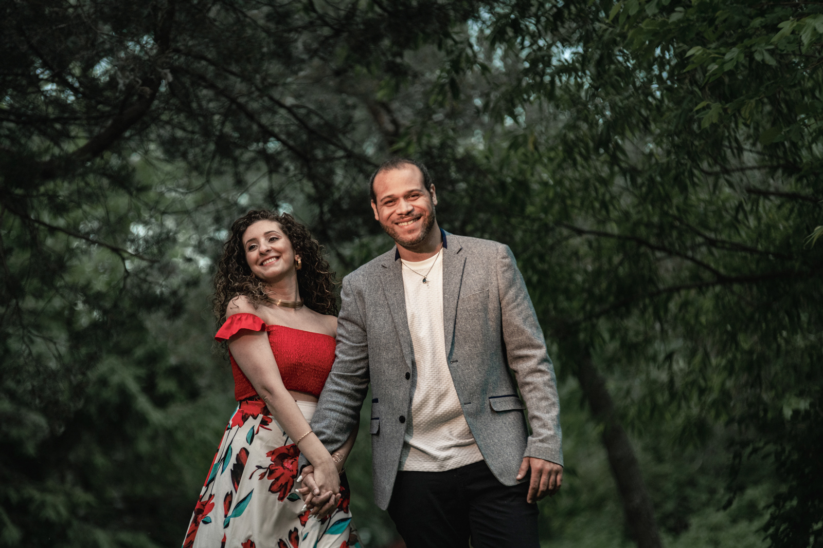 Engagement session in a park, couple holding hands and smiling together.
