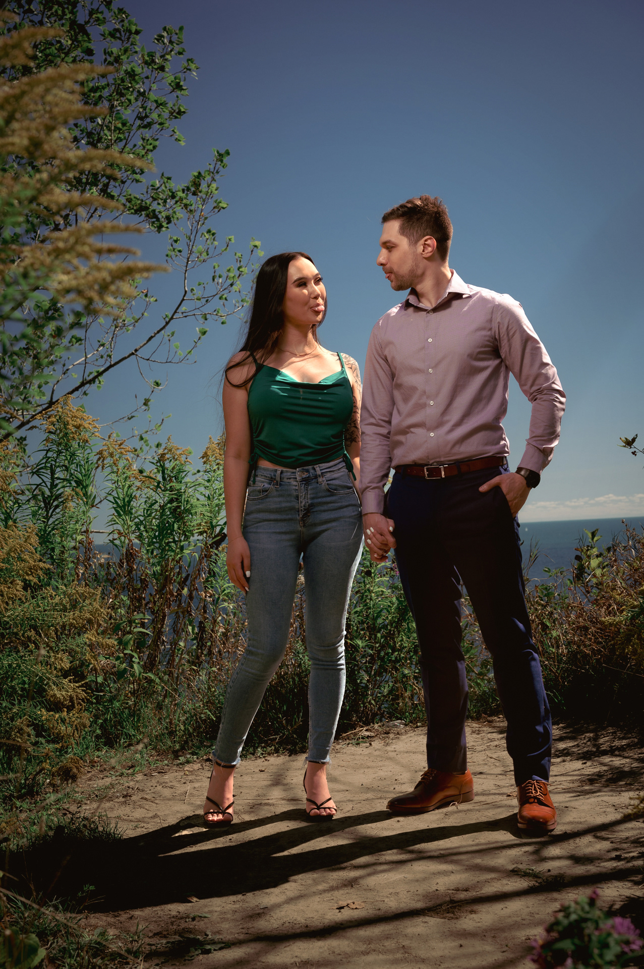 Engaged couple standing along the Scarborough Bluffs trail, lake in the distance.