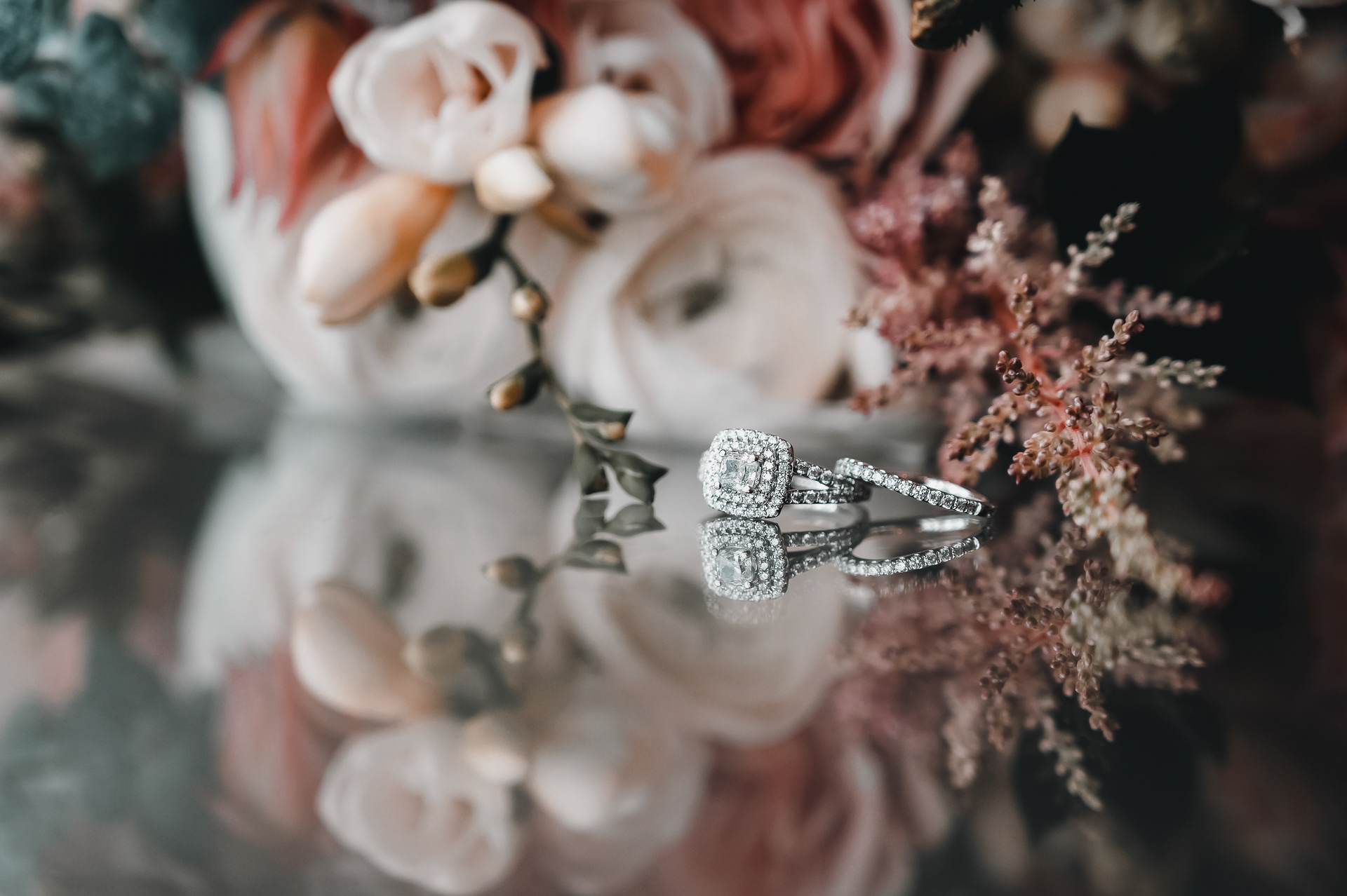 Wedding rings placed on pink and white bouquet before ceremony.