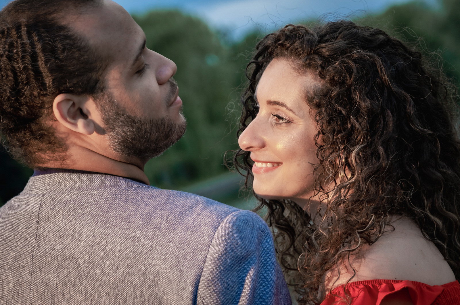 Romantic couple gazing at each other lovingly with soft evening light in the park.
