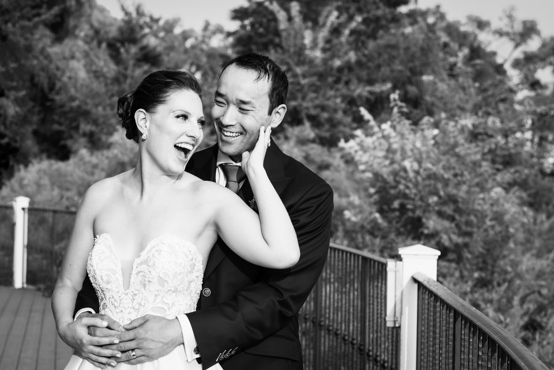 Bride laughing joyfully while groom holds her close on the terrace.