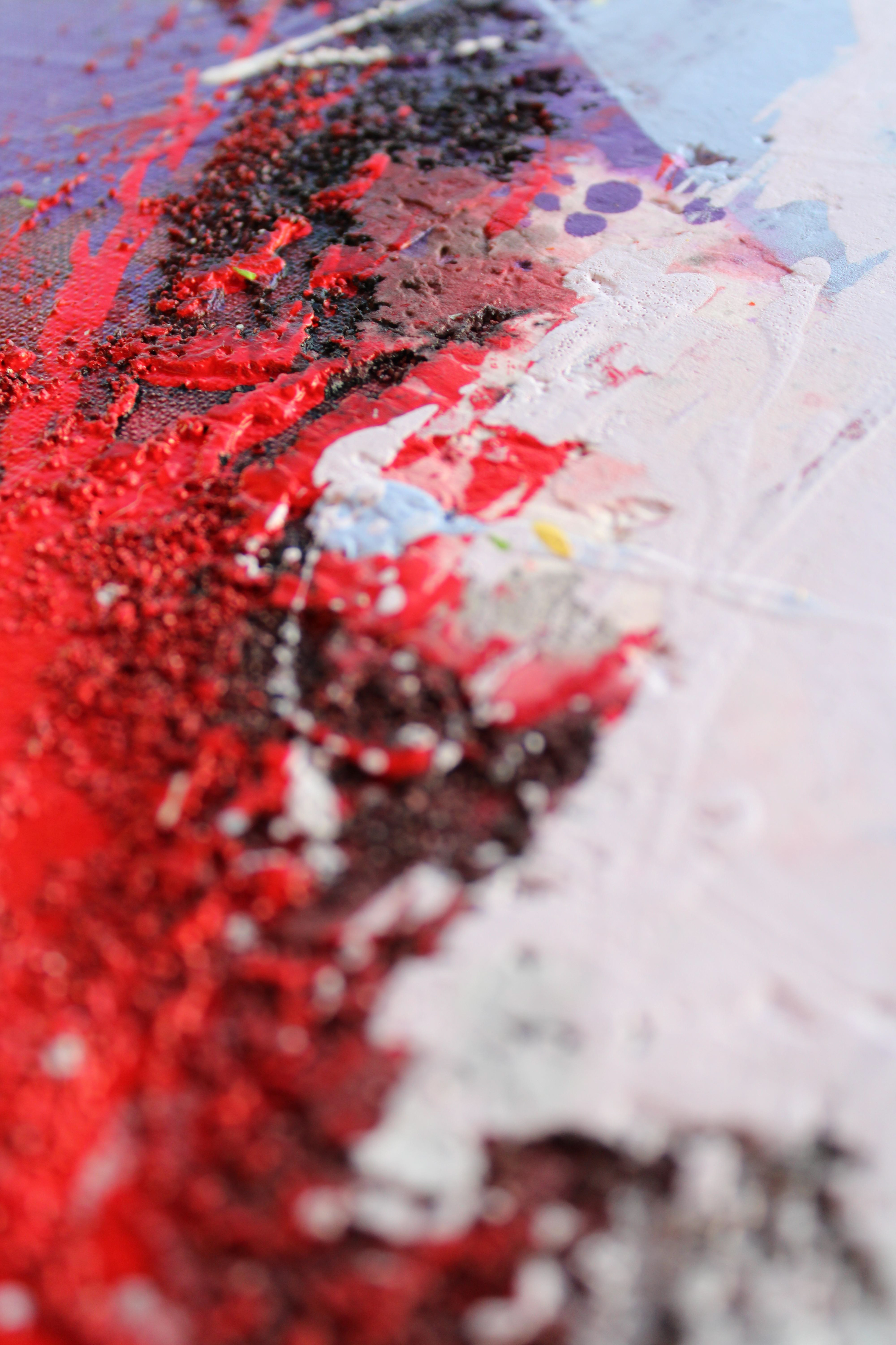 (Close-up center Detail) - This close-up captures the dramatic contrast and material density of the artwork, where a vibrant, textured field of red and black collides with soft pastel lilac tones. The coarse relief work creates a physical separation between the layers, highlighting the complex build-up of paint.