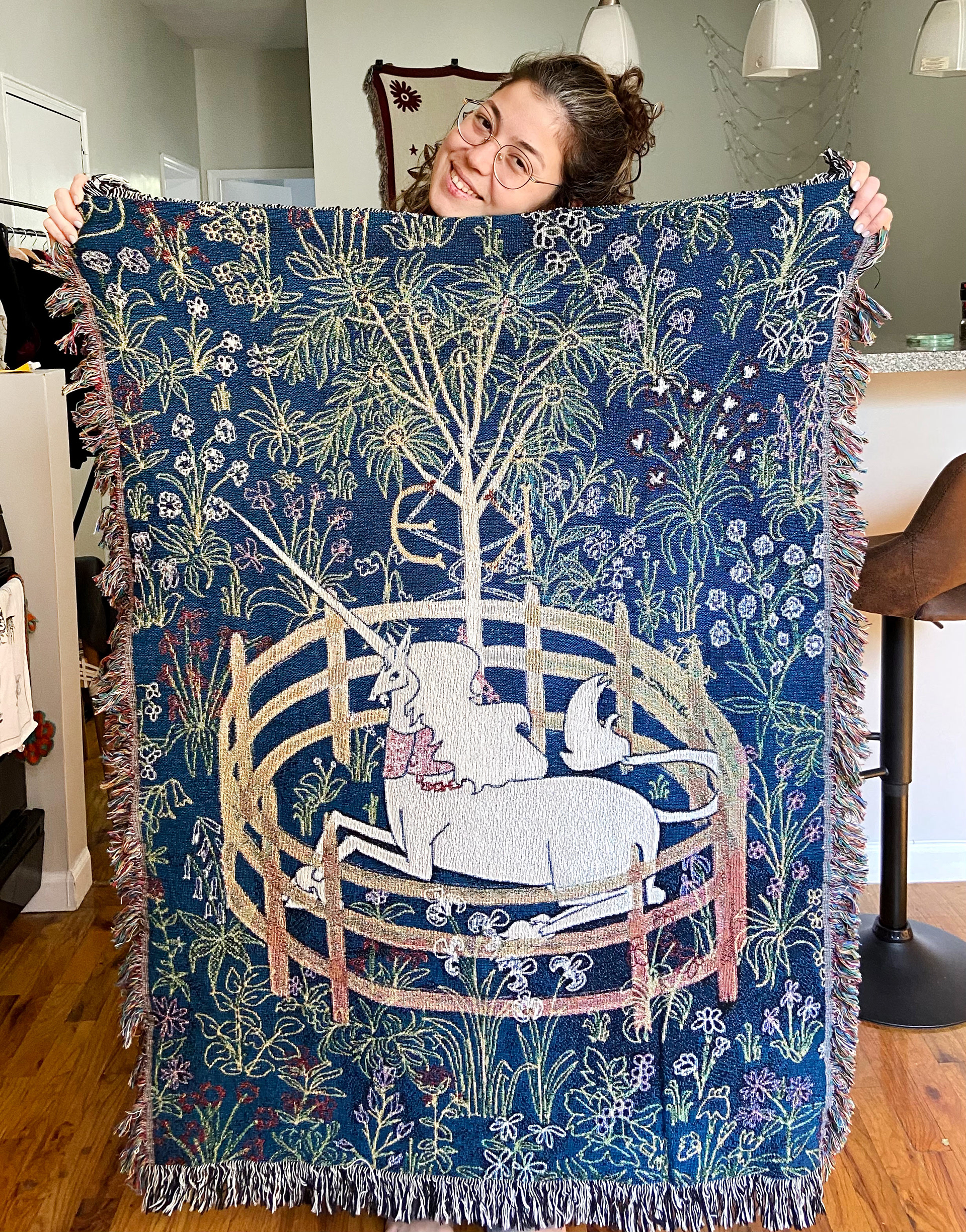 Edanur Kuntman holding her own unicorn tapestry.