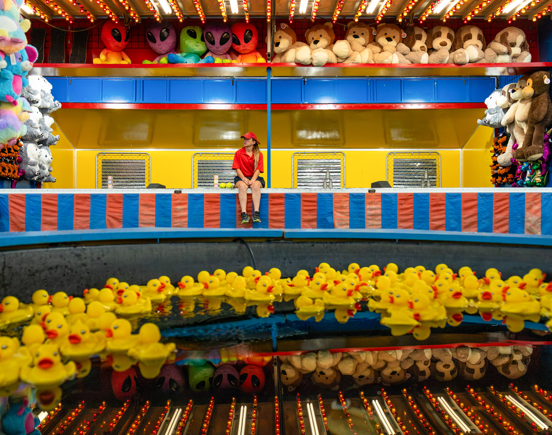 A carnival worker sits and waits for attendees as the fair first opens at the Marion County Fair in Lebanon, Kentucky, on July 7, 2026. Less than one hundred people attended the Marion County Fair due to the weather.