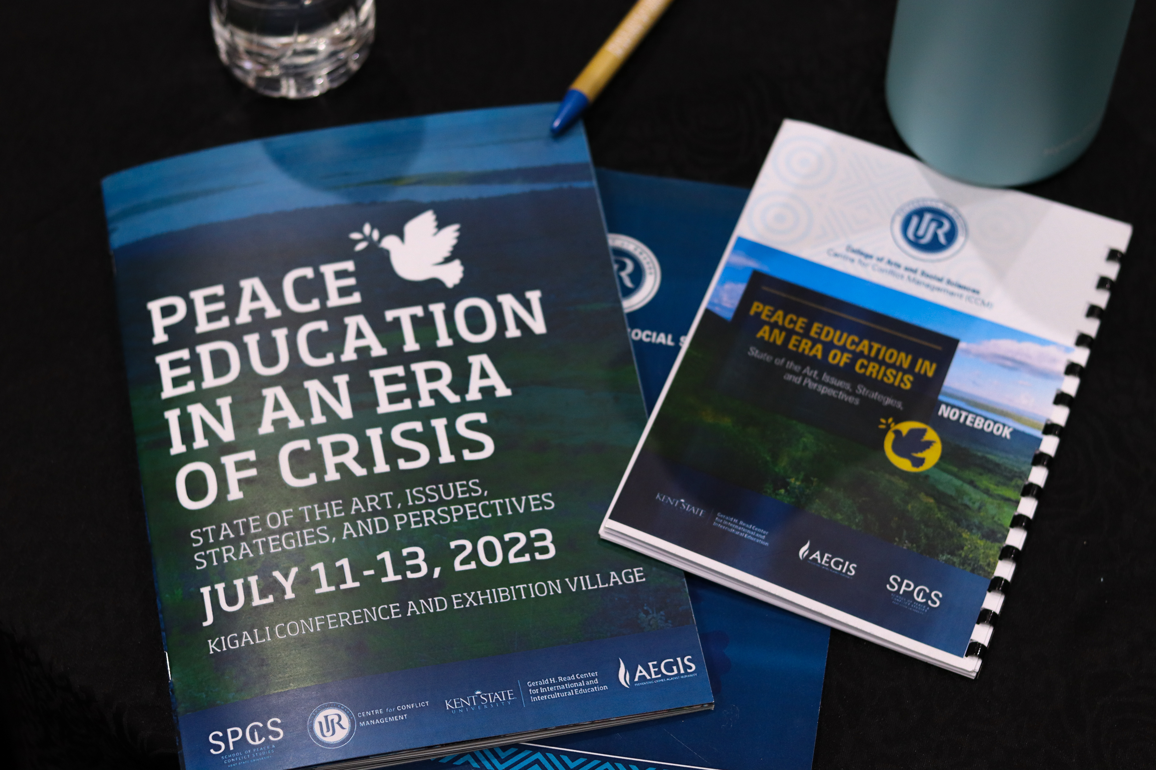 The Peace Education conference program laid on a table next to a notebook and pen.
