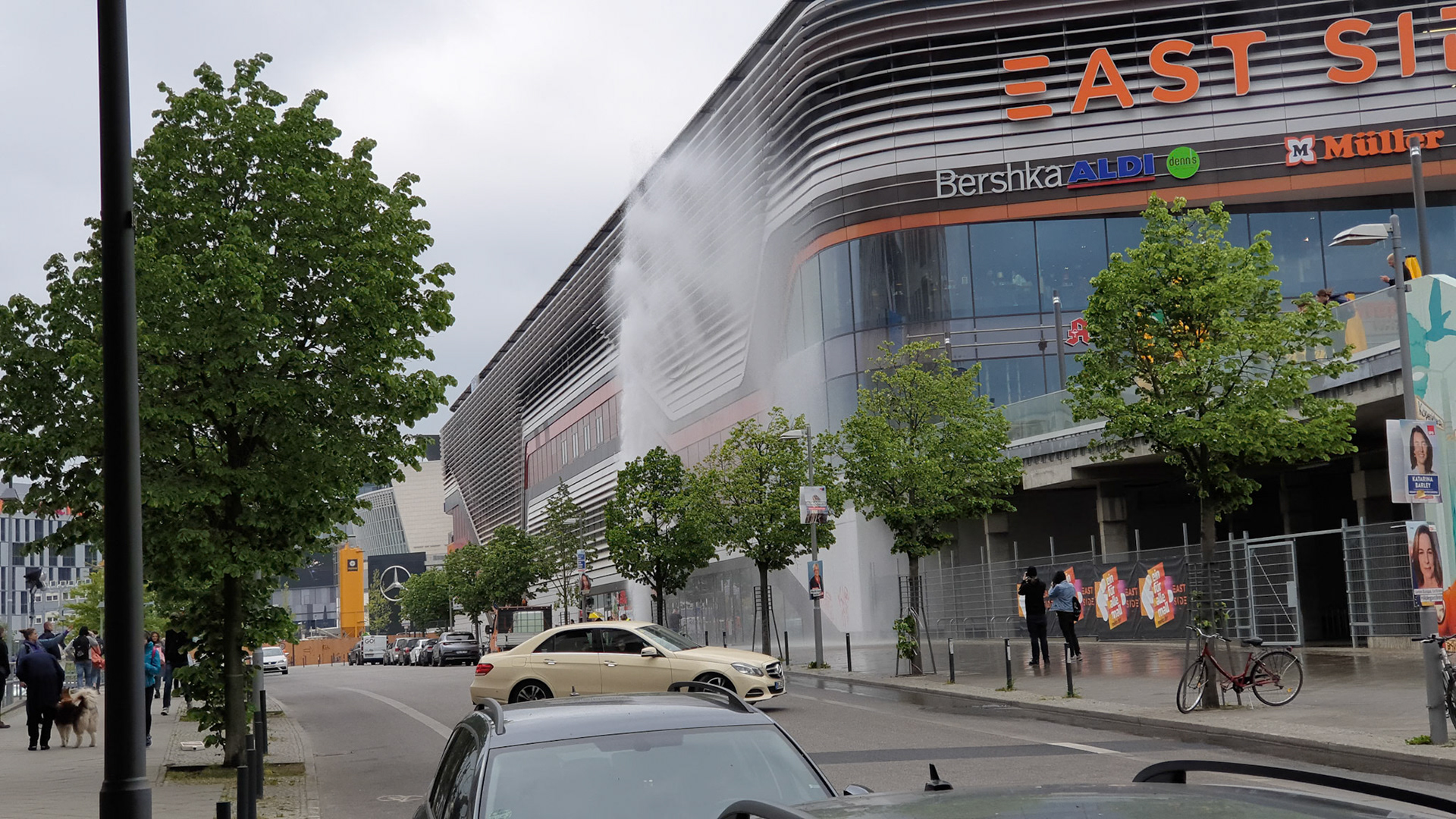 Wet shopping center near open fire hydrant in Berlin.