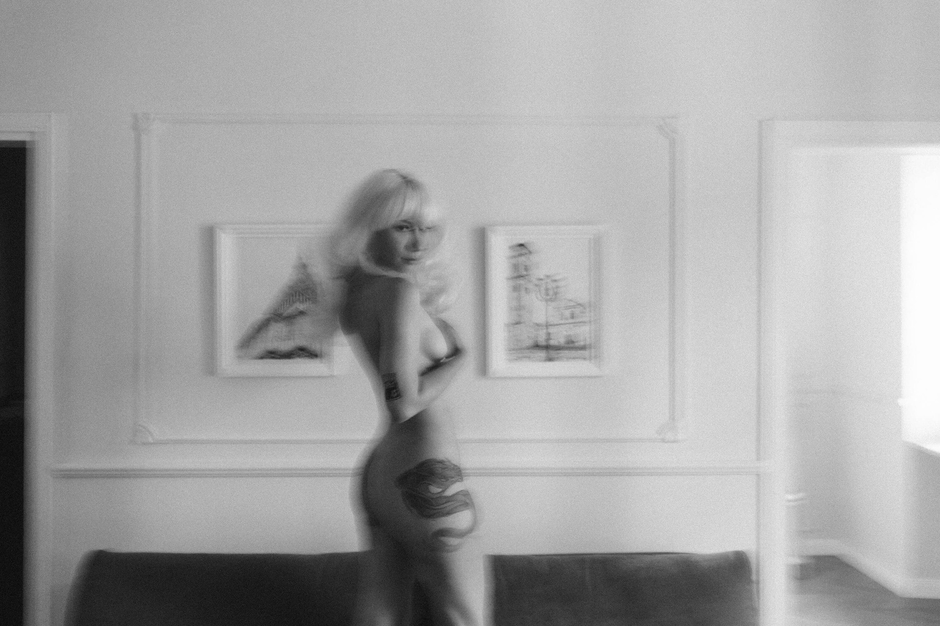 Blurred nude female figure moving in an interior space with soft light
