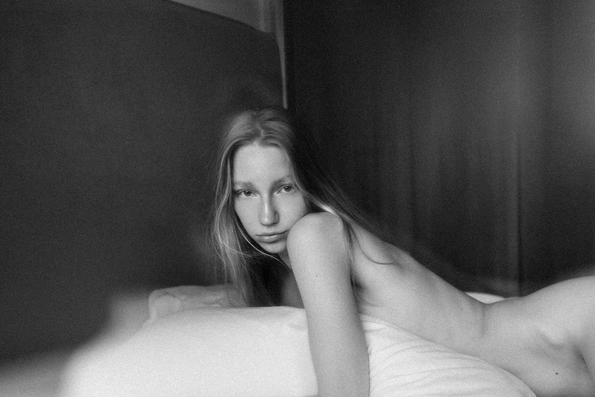 fine art nude portrait of woman lying on bed in soft natural light