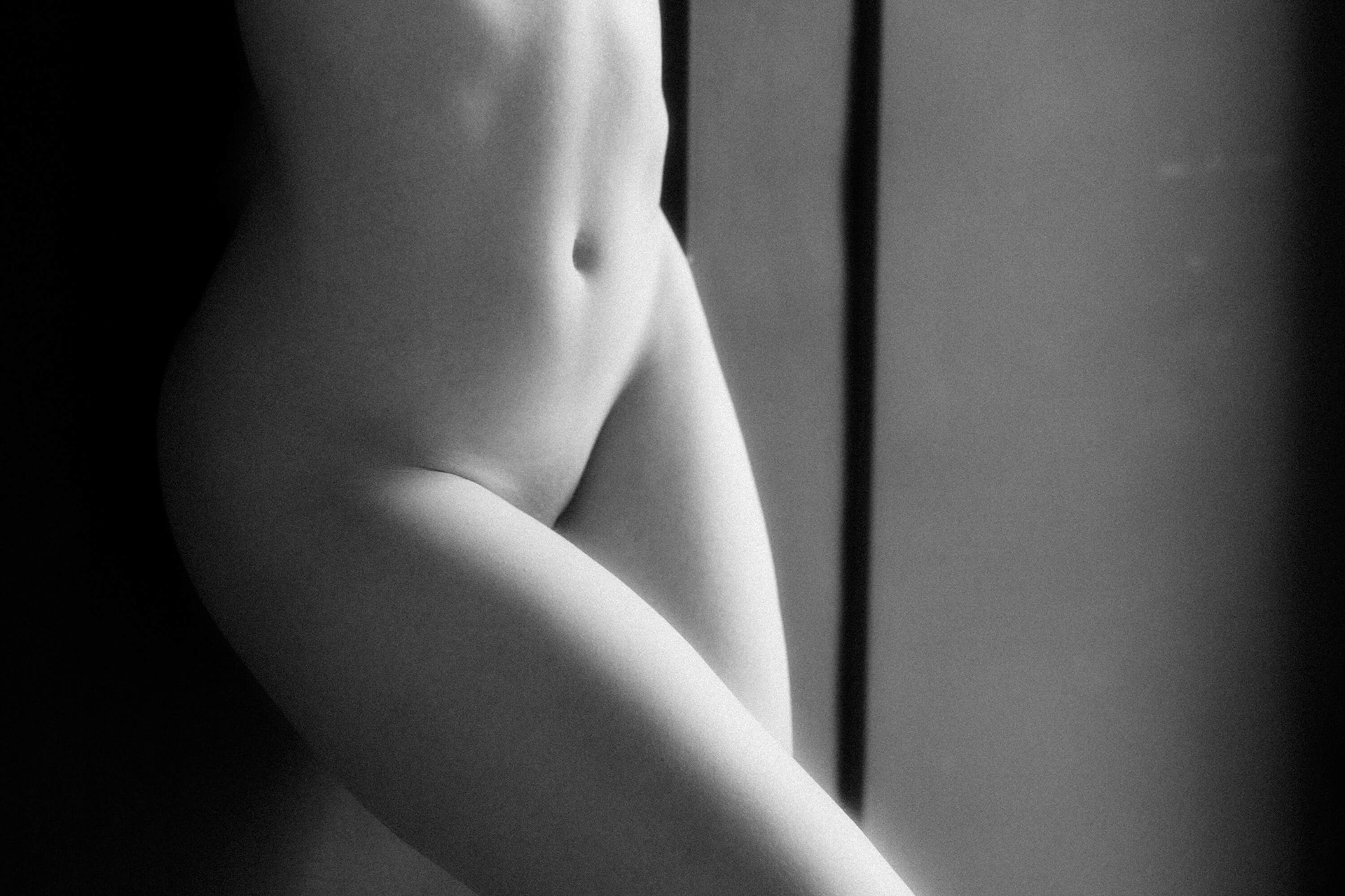 Abstract nude detail of female hips and thighs with soft shadows