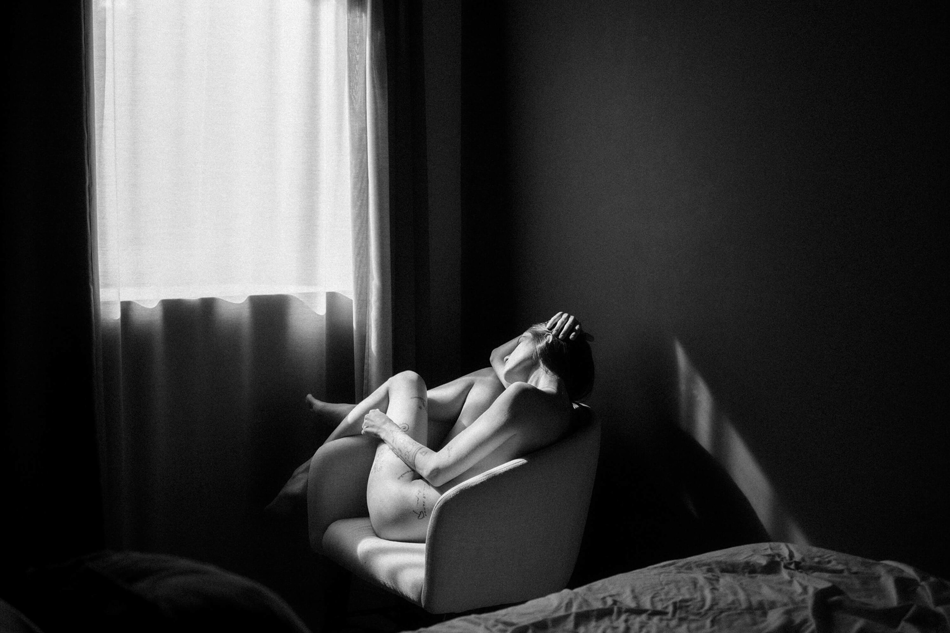 fine art nude woman seated in chair with side window light