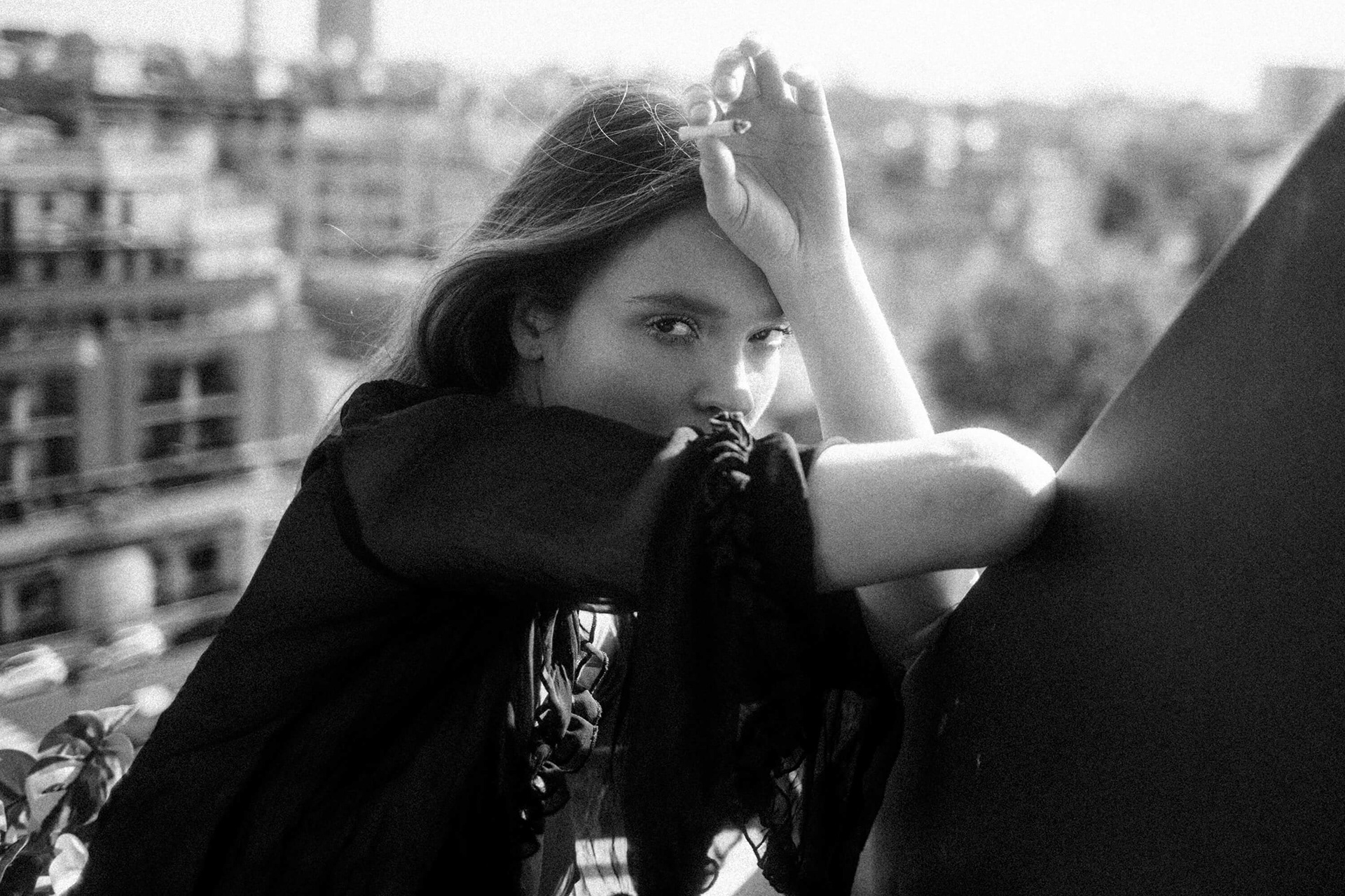 Fine art portrait of a woman with arm raised, soft focus city background