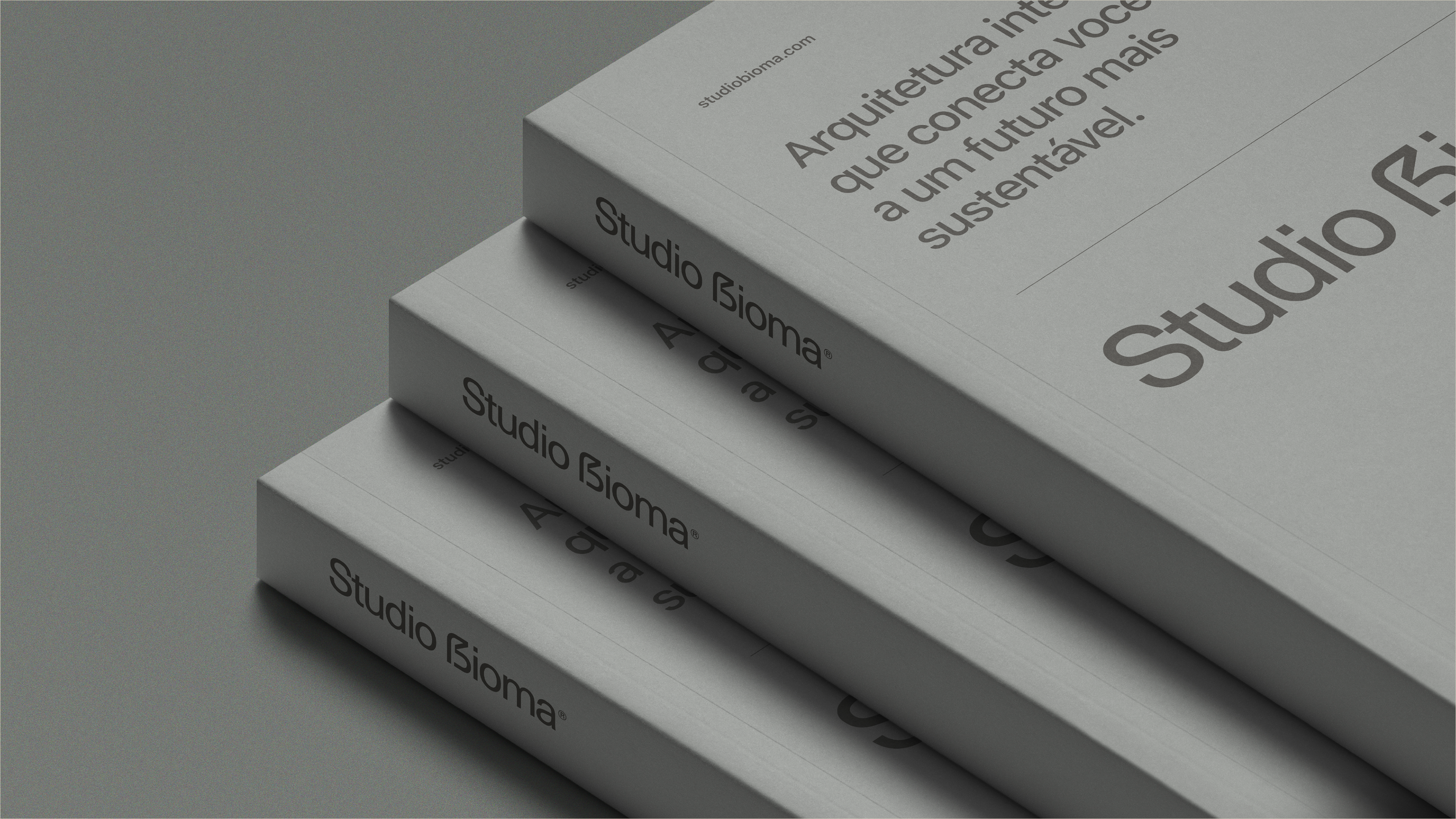 Livros institucionais do Studio Bioma empilhados – branding editorial com mensagem sustentável e arquitetura inteligente.