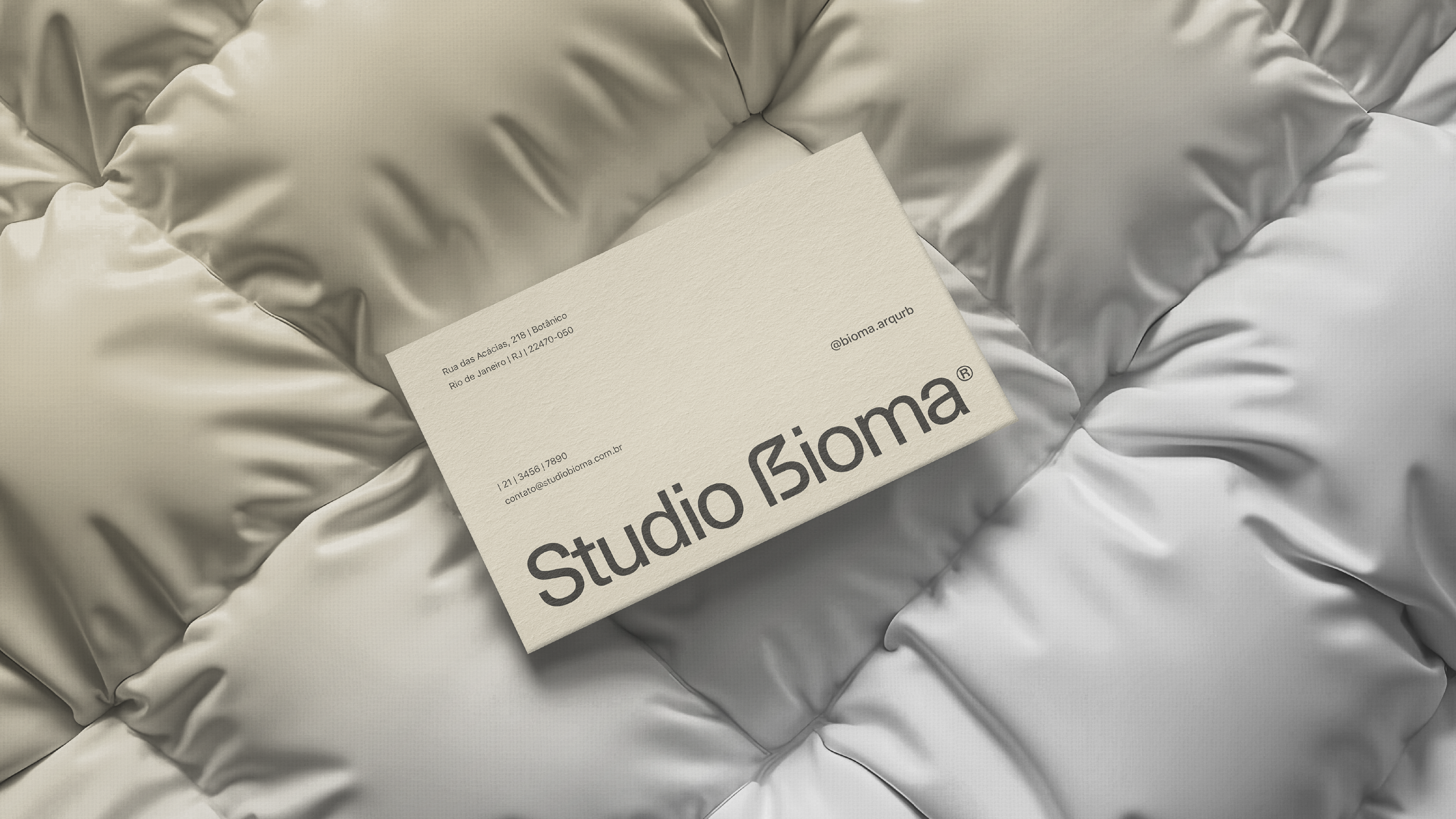 Cartão de visitas do Studio Bioma sobre superfície acolchoada – aplicação elegante de branding com foco em arquitetura autoral.
