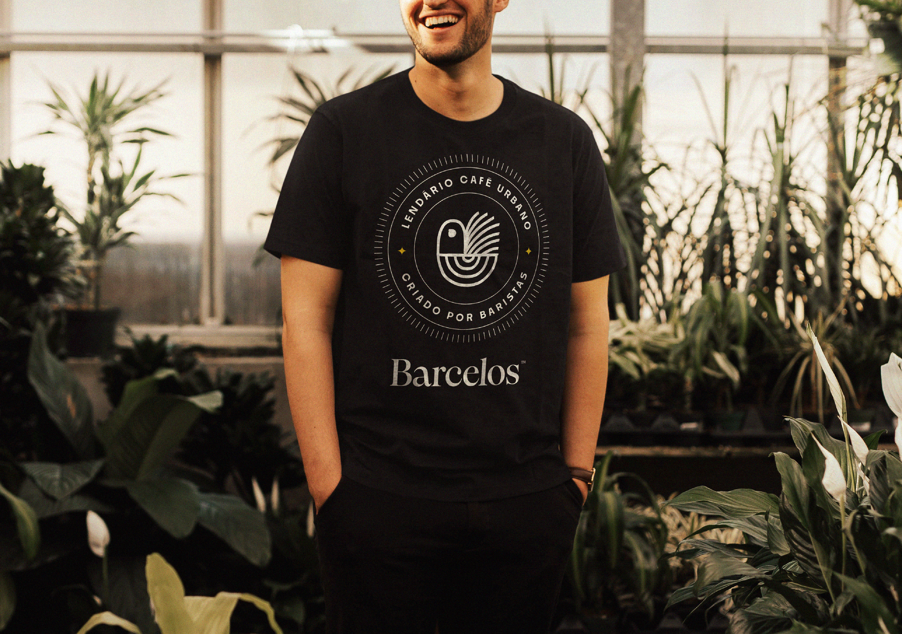 Camiseta preta com logo Barcelos e selo circular "Lendário Café Urbano", exemplificando aplicação de marca em merchandising e identidade visual coerente para design de uniformes.