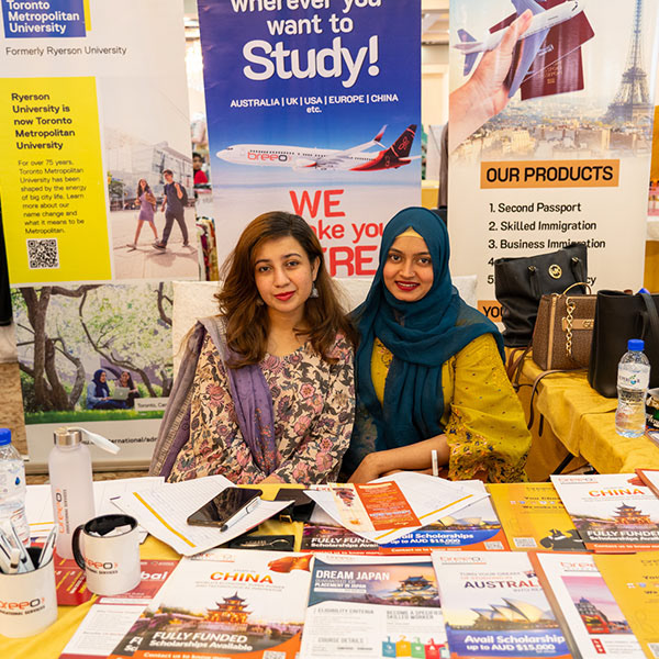 Promotional brand photo – two women posing at trade show booth in Lahore