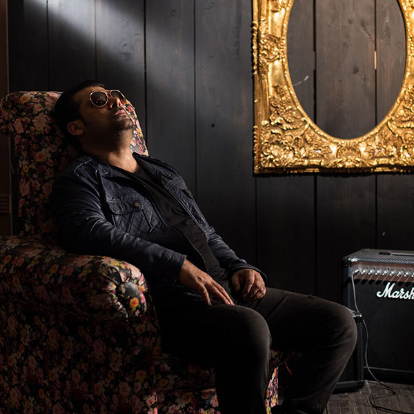 Male musician sitting on sofa for a stylized poster shoot – artist branding and promo photography