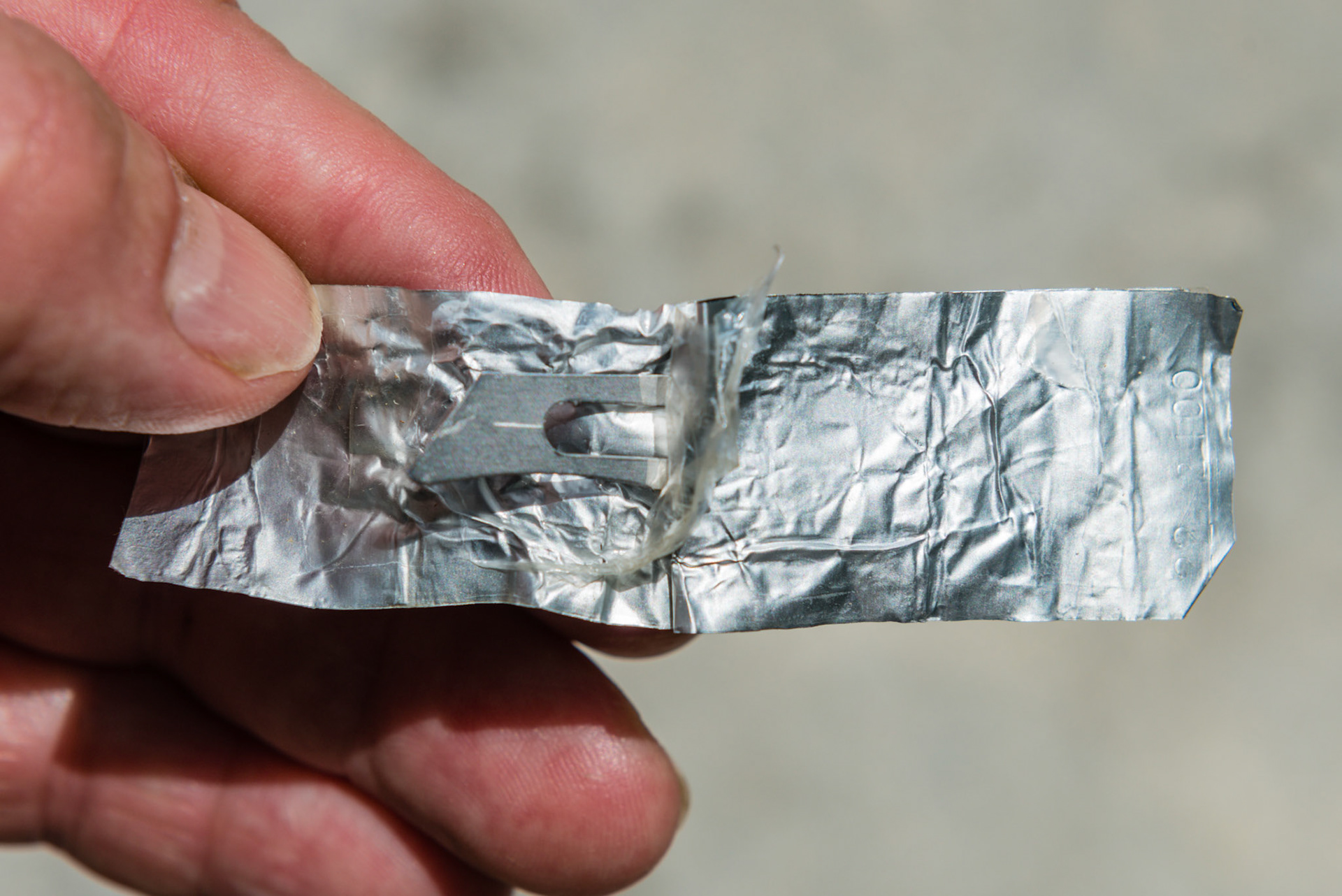 A #22 surgical blade coming out of its wrapper.